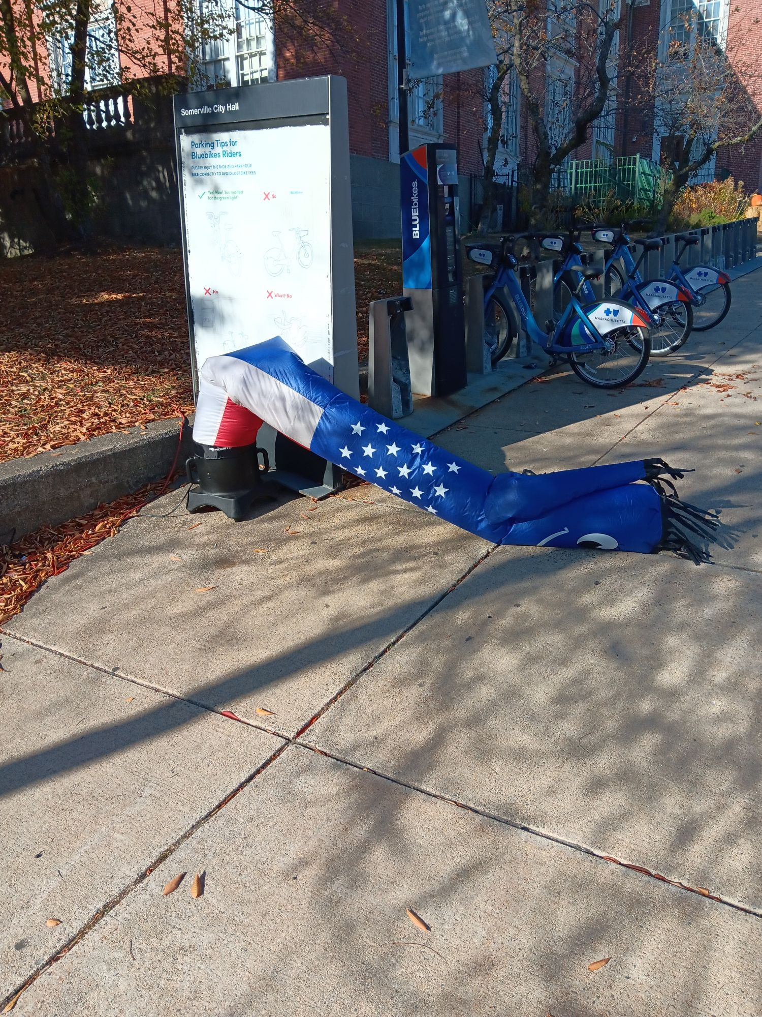 The america-themed wavy air guy at Somerville's early voting location is lying face down on the ground, half-deflated