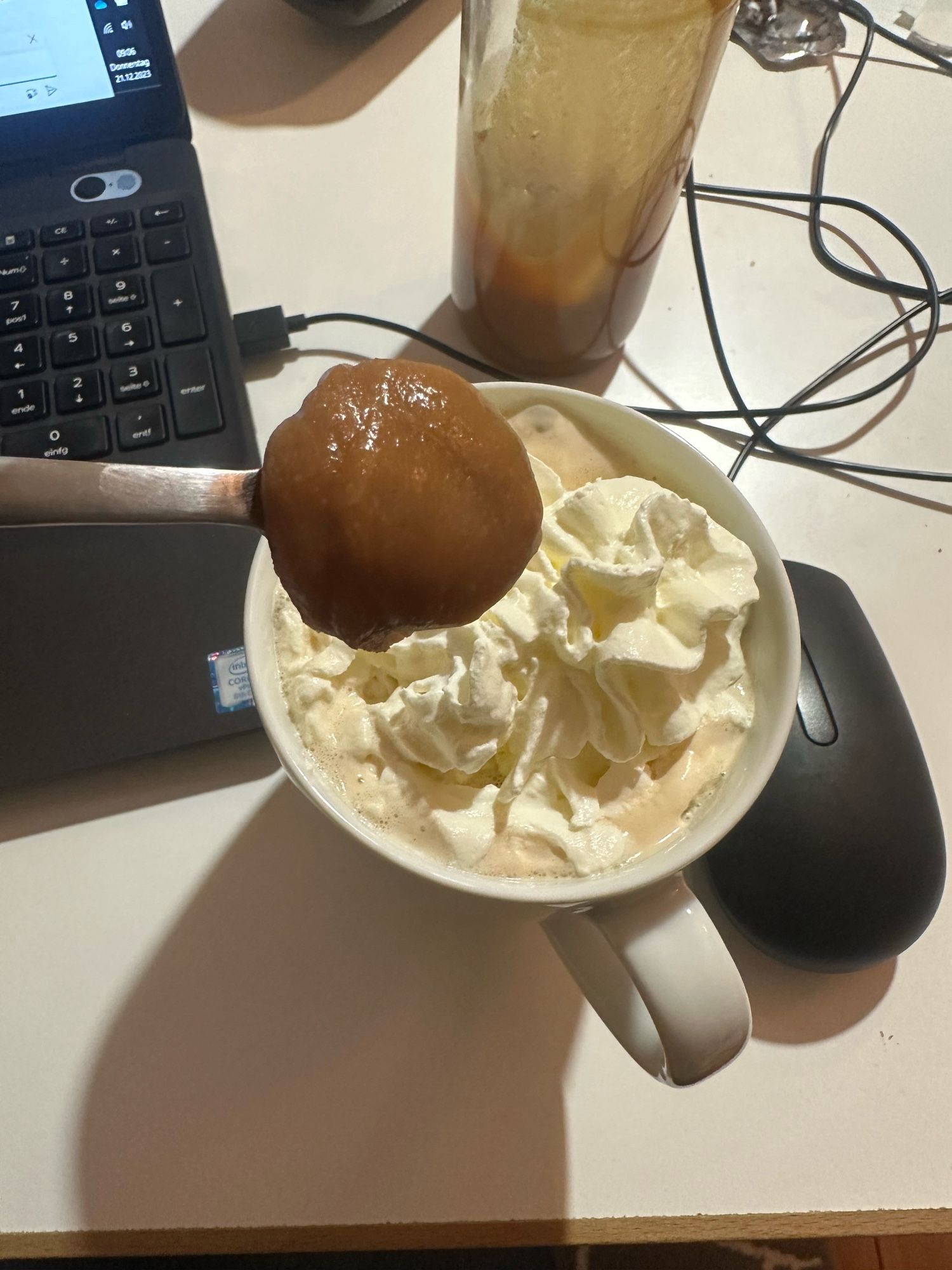 Eine Kaffeetasse vor einem Rechner, darüber ein Espresso-Löffel mit einem Blob selbstgemachtem Salzkaramell.