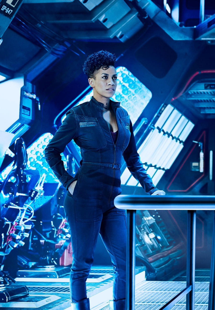 Dominique Tipper playing Naomi Nagata, standing on the Rocinante's blue lit flight deck
