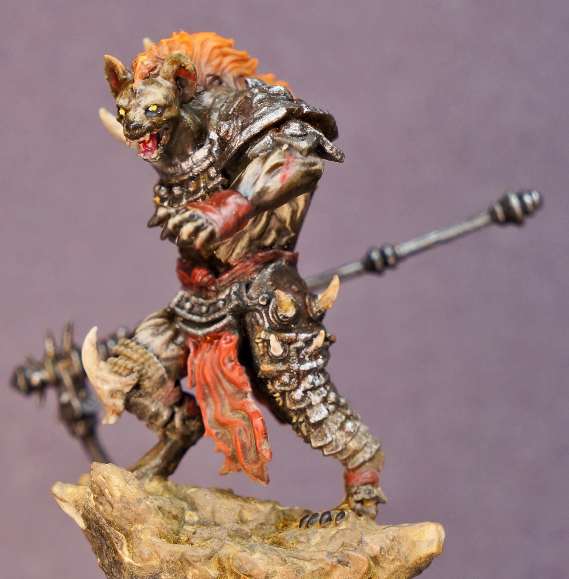 A photo of a handpainted gnoll mini figurine. The gnoll is clad in armour and wields a huge bone scythe