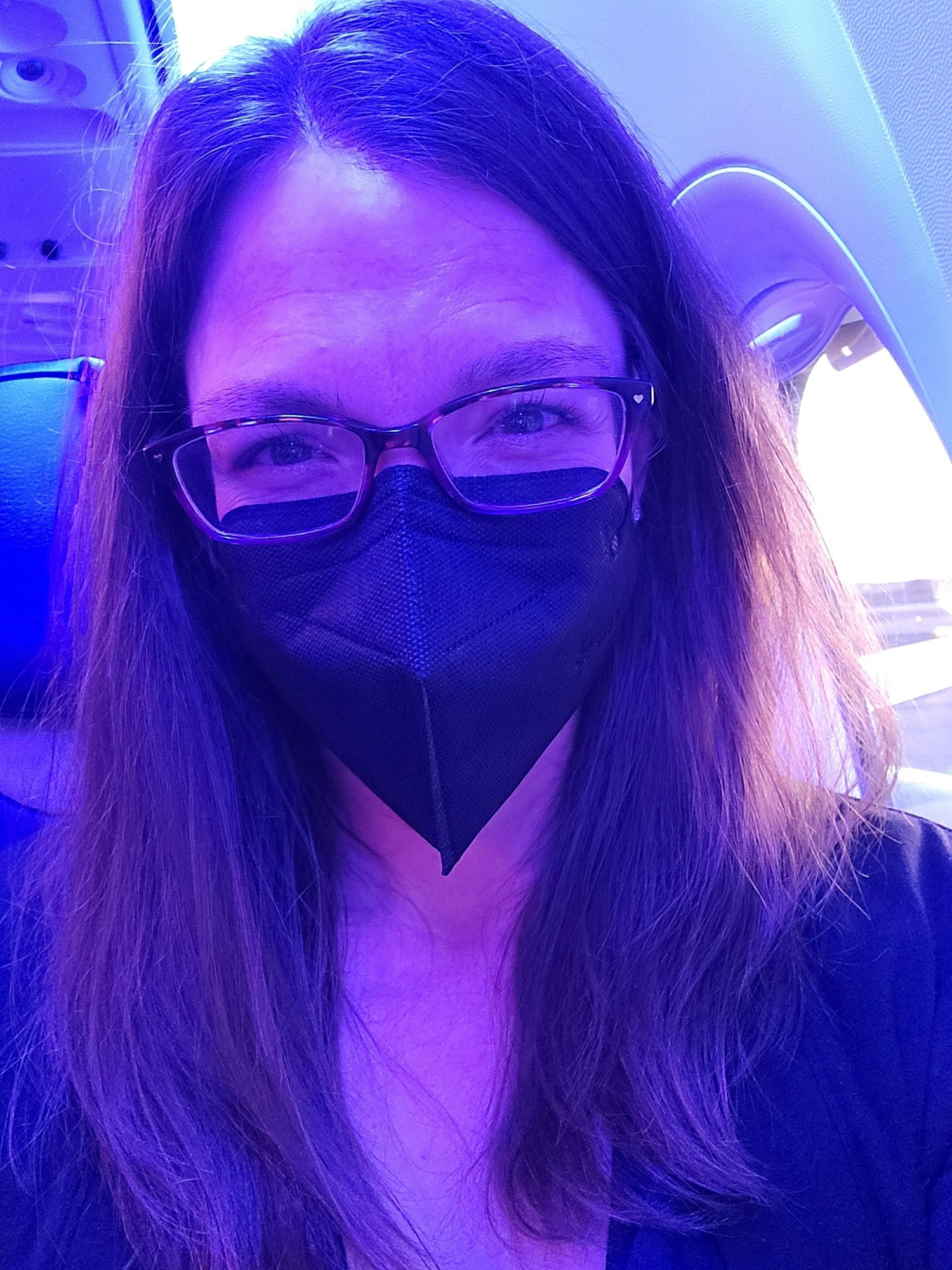 selfie in a black mask in blue light on plane.