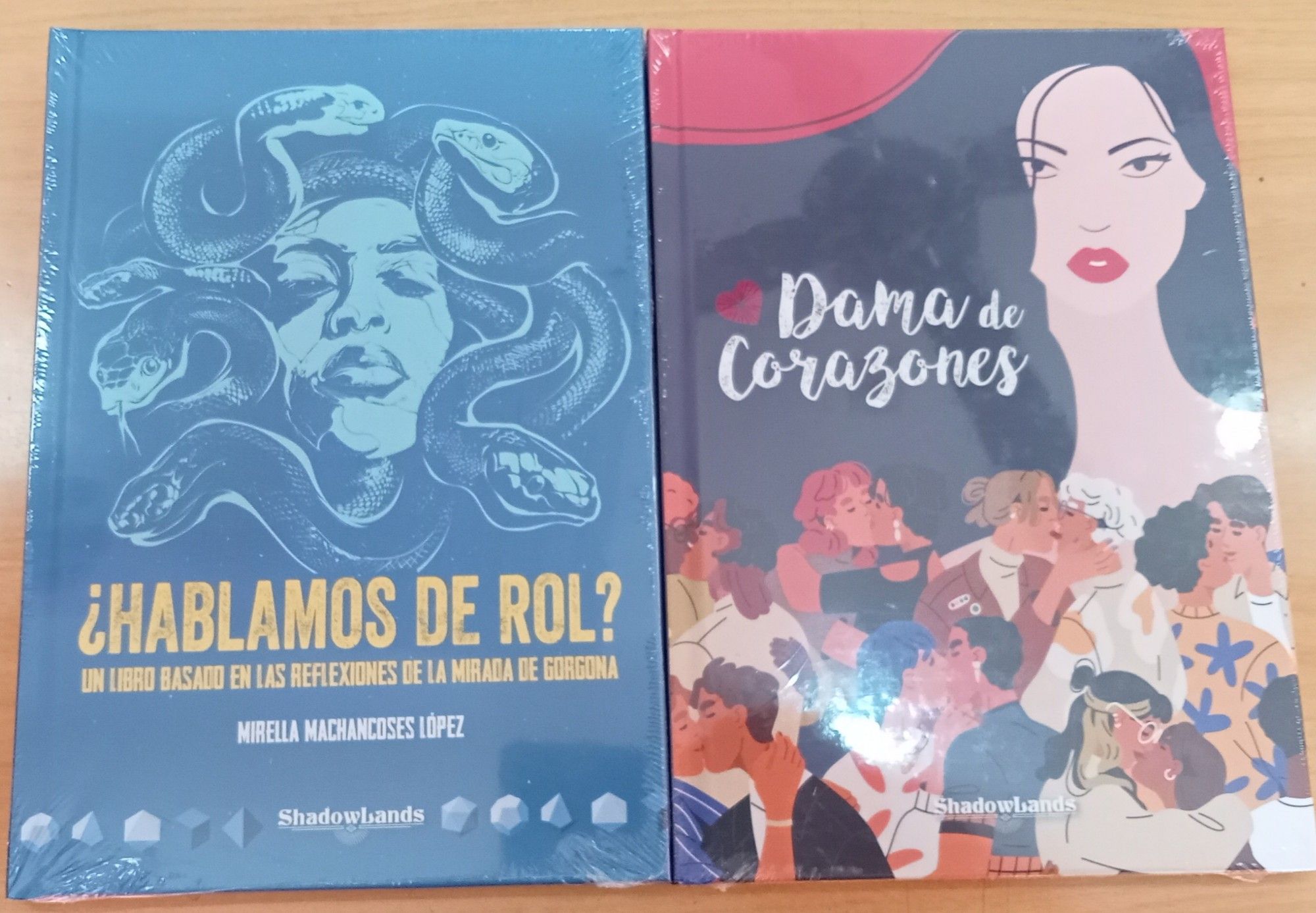 A la izquierda la portada en azul con el título "¿Hablamos de rol?" en la parte inferior. Ocupando los dos tercios superiores el rostro de una gorgona con las serpientes en lugar de cabellos. 
A la derecha la colorida portada de "Dama de Corazones". La mitad superior está ocupada por el título a la izquierda y el rostro de unas mujer con largos cabellos negros. La parte inferior muestra unas 7 u 8 parejas de todo tipo de edad, etnia, orientación sexual, clase social, etc. besándose