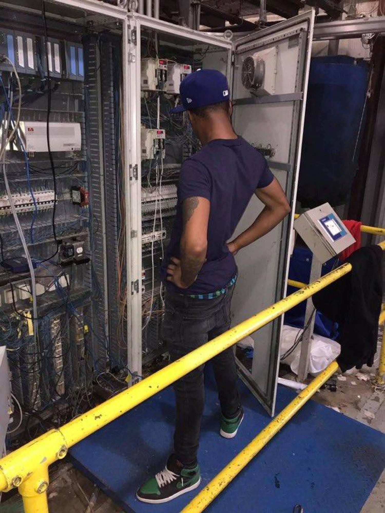 man with his hands on his hips looking confusedly at the inside of a server rack