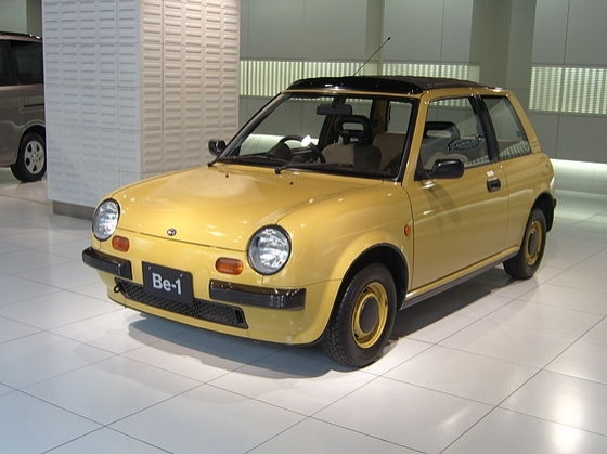 The Nissan Be-1 in Pumpkin Yellow. It is a Notchback Sedan. Like the Figaro, it is based on the Nissan Micra.