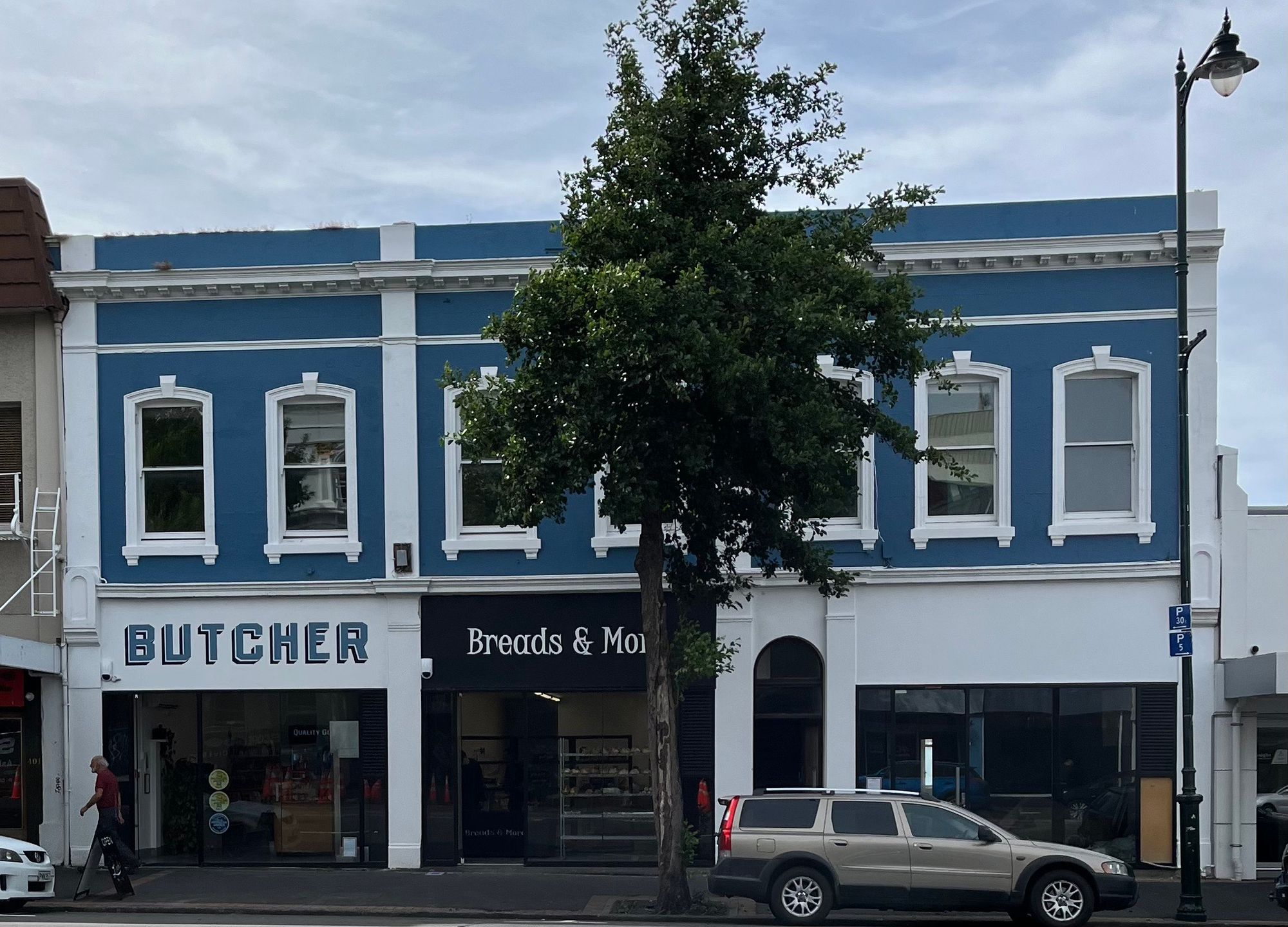 Three businesses, from left to right a butcher, a bakery named Breads & More, and an empty shop.