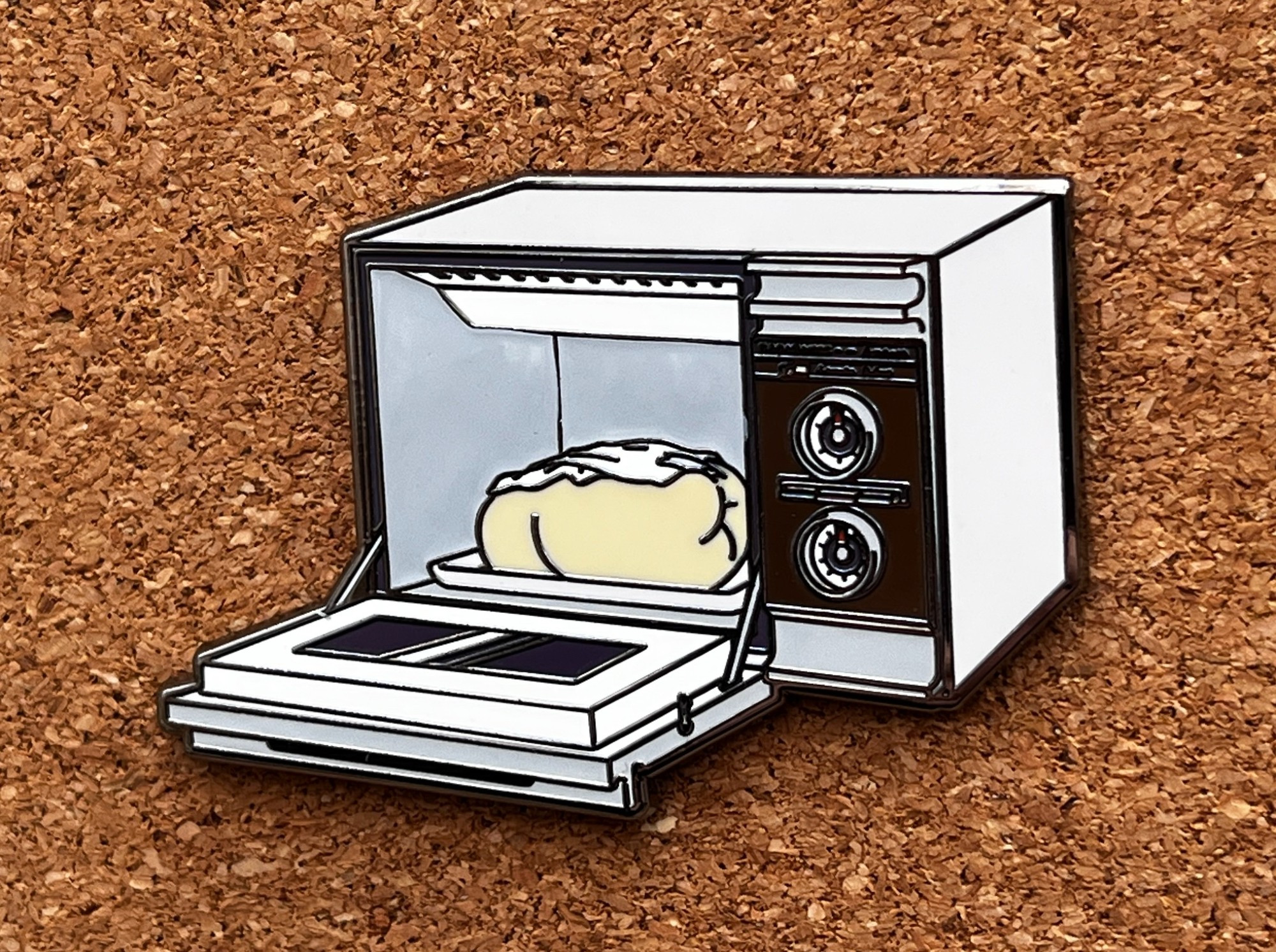 Image is of an enamel pin. The design is of a vintage microwave (which opens like a conventional oven) with the door open. Inside is a rolled up, used/wet diaper.