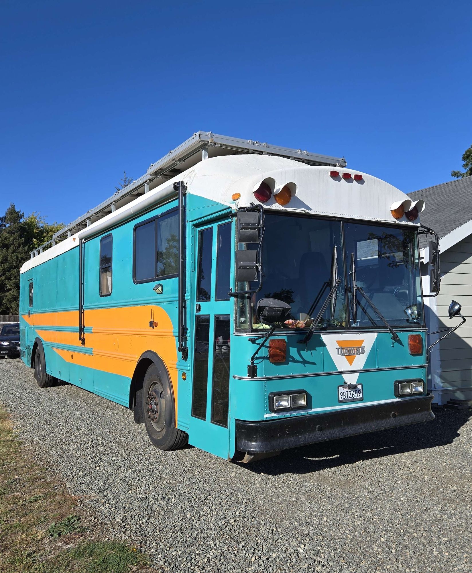 Photo of a 38ft blue and orange bus with a raised roof.