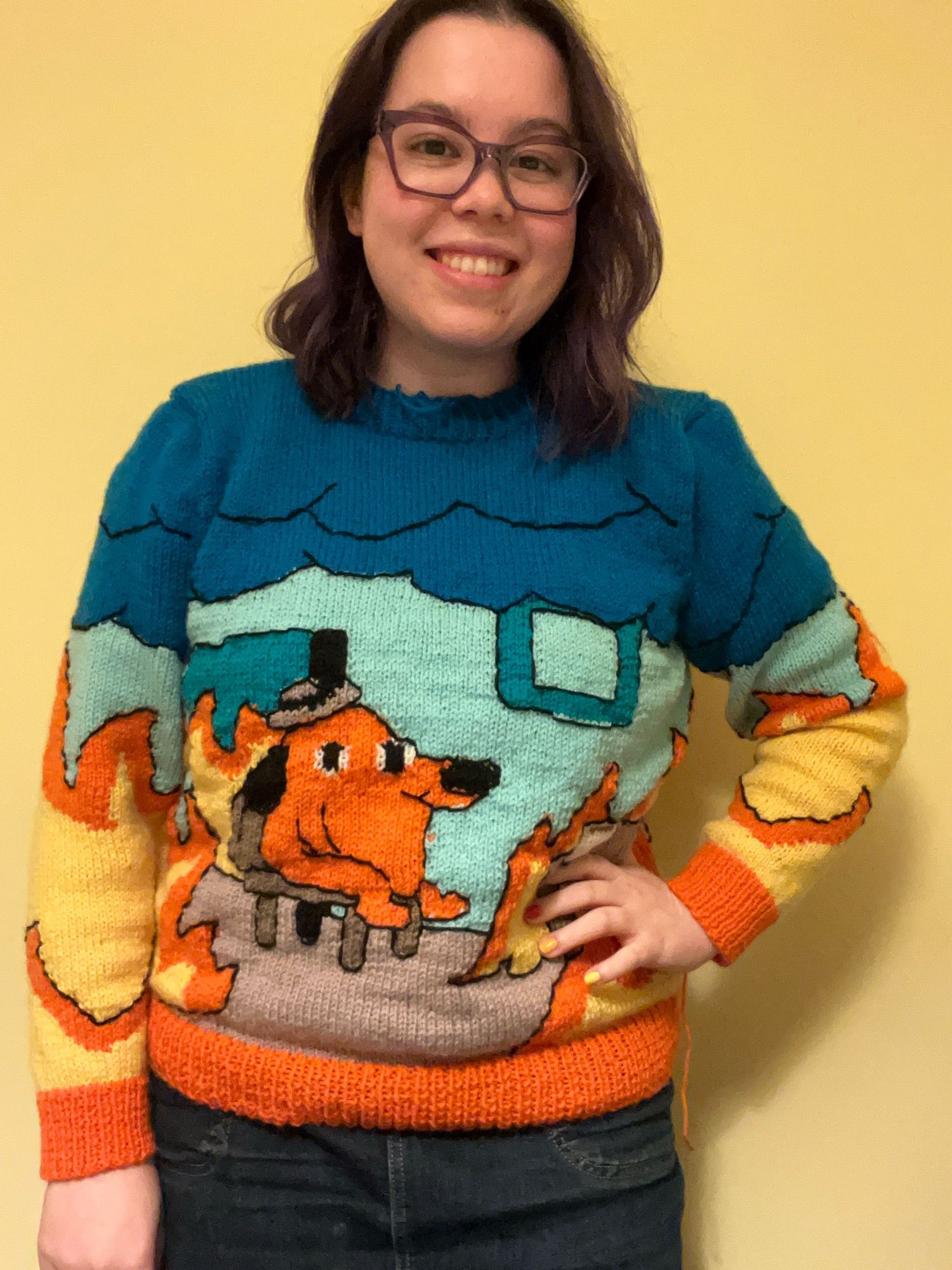 I’m wearing a hand knitted jumper of the ‘this is fine’ meme. It features an orange dog sat in a blue building which is on fire, yet the dog appears unphased