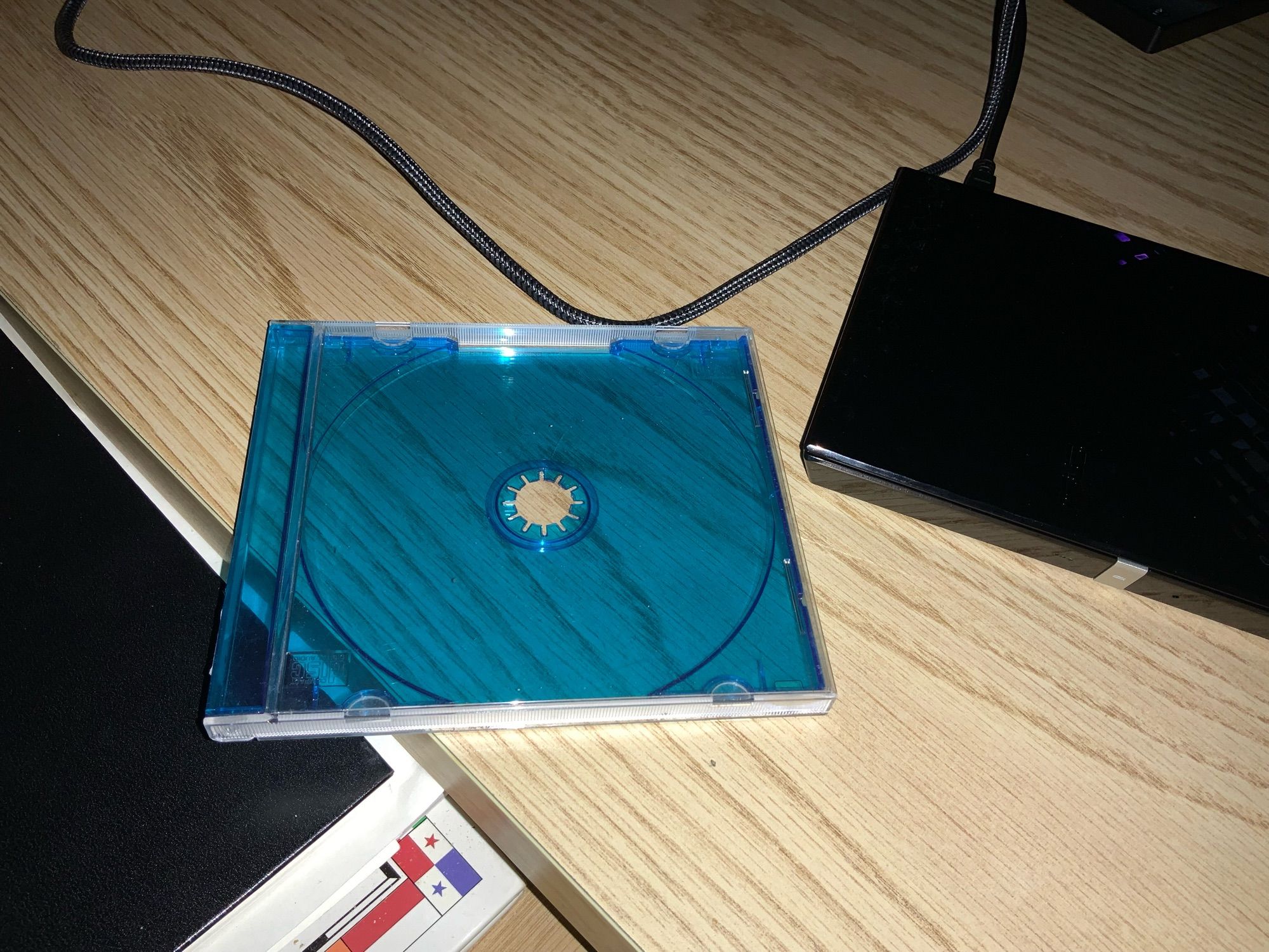 On a desk, an old transparent cd case by a portable cd player.