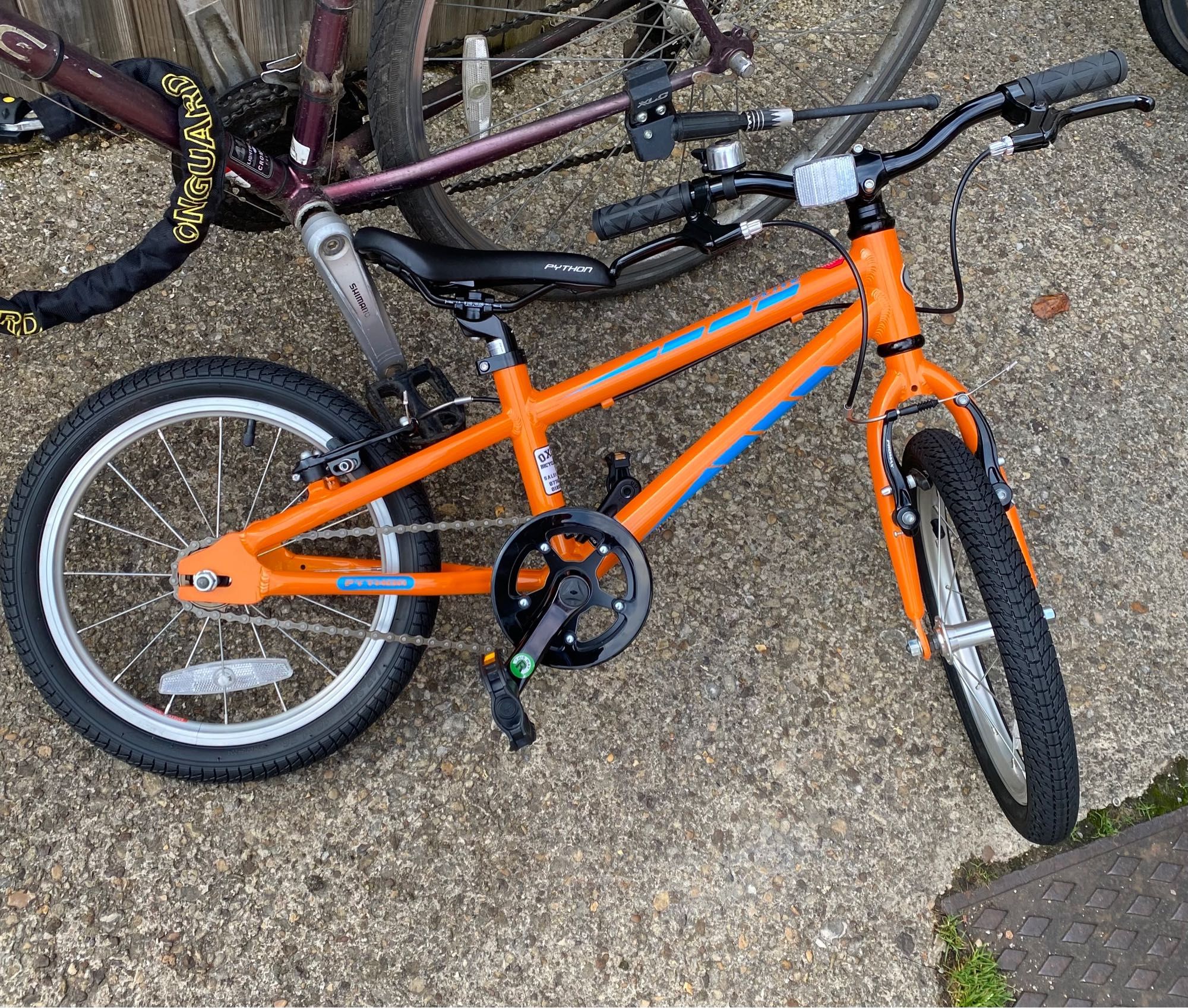 A brand-new orange bike with no mudguards.