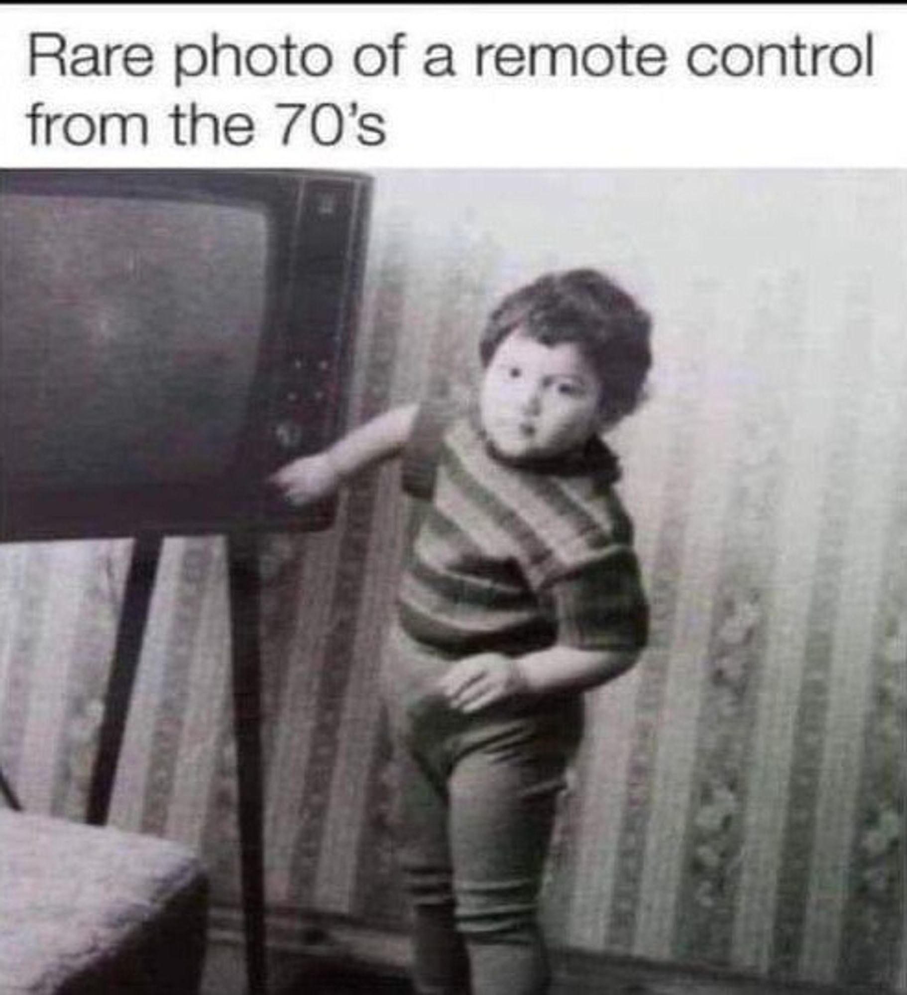 Black and white photo: Child standing beside a television, using a dial on it to change the channel with their hand.
Text: Rare photo of a remote control from the 70's.