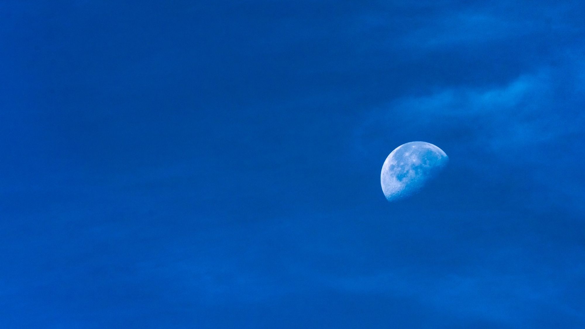 Halbmond bei Tag am blauen Himmel mit leichten Schleierwolken