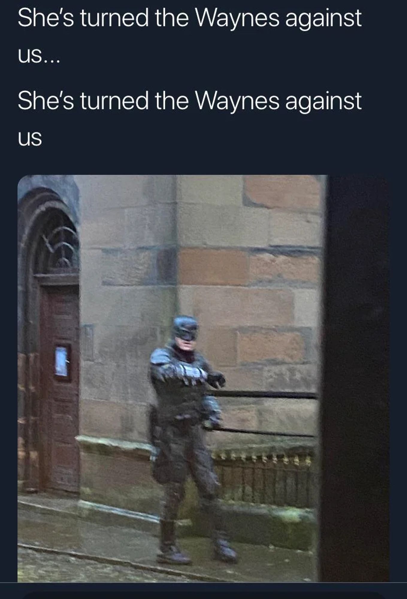 Blurry image of a man in a (partial?) Batman costume, on  wet Glasgow street.

Text: She’s turned the Waynes against us…

She’s turned the Waynes against us…