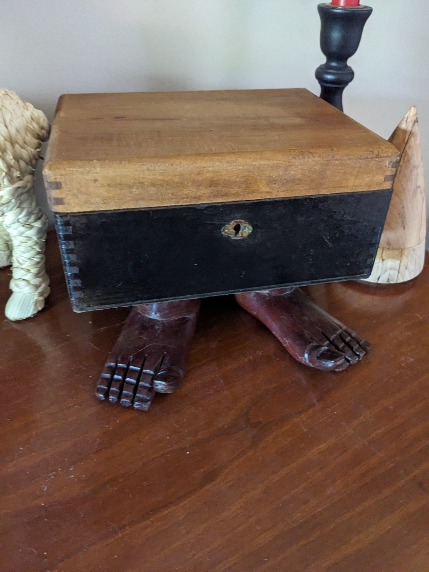 A simple box with a keyhole, but it stands on 2 carved wooden feet, big toes pointed up