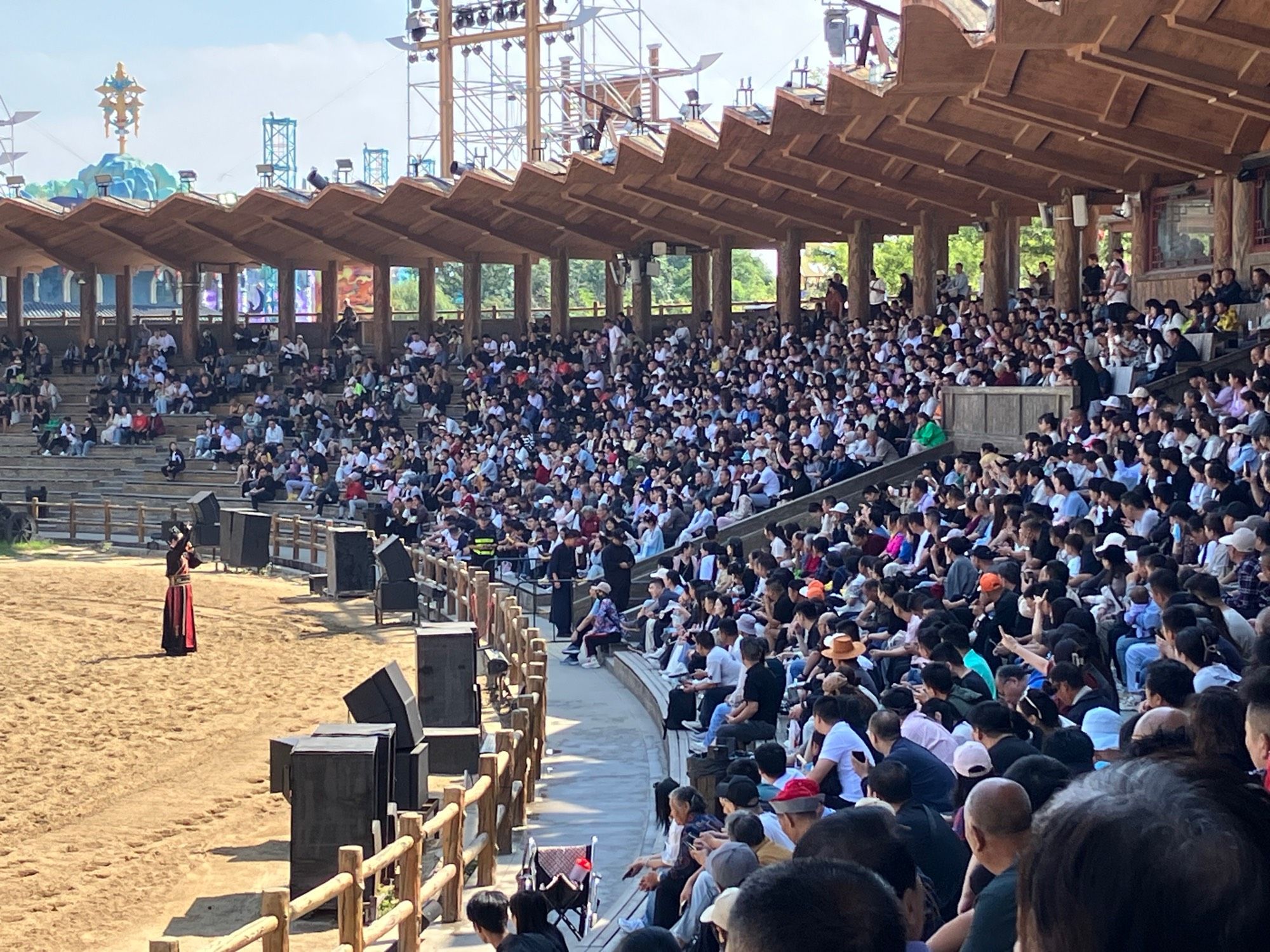 Crowds in an arena about to watch a battle between opposing forces with horses and cannons and exploding arrows. Story from the Song of three kingdoms.