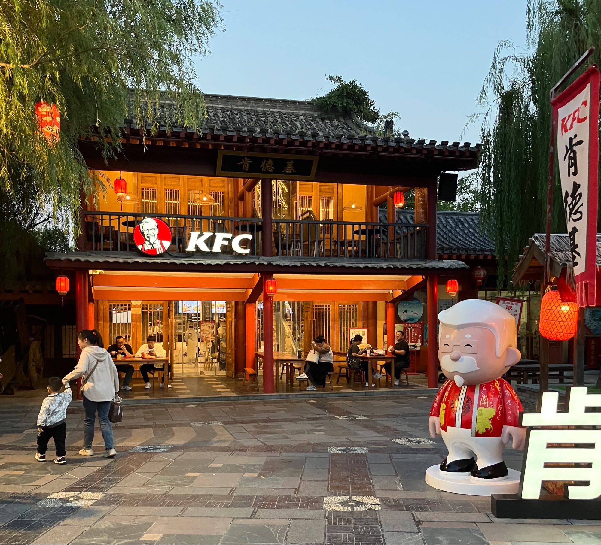 A KFC inside a Song era style building with a statue of what I can only imagine is Colonel Sanders’ Chinese cousin outside. He’s dressed in red Chinese style dress.