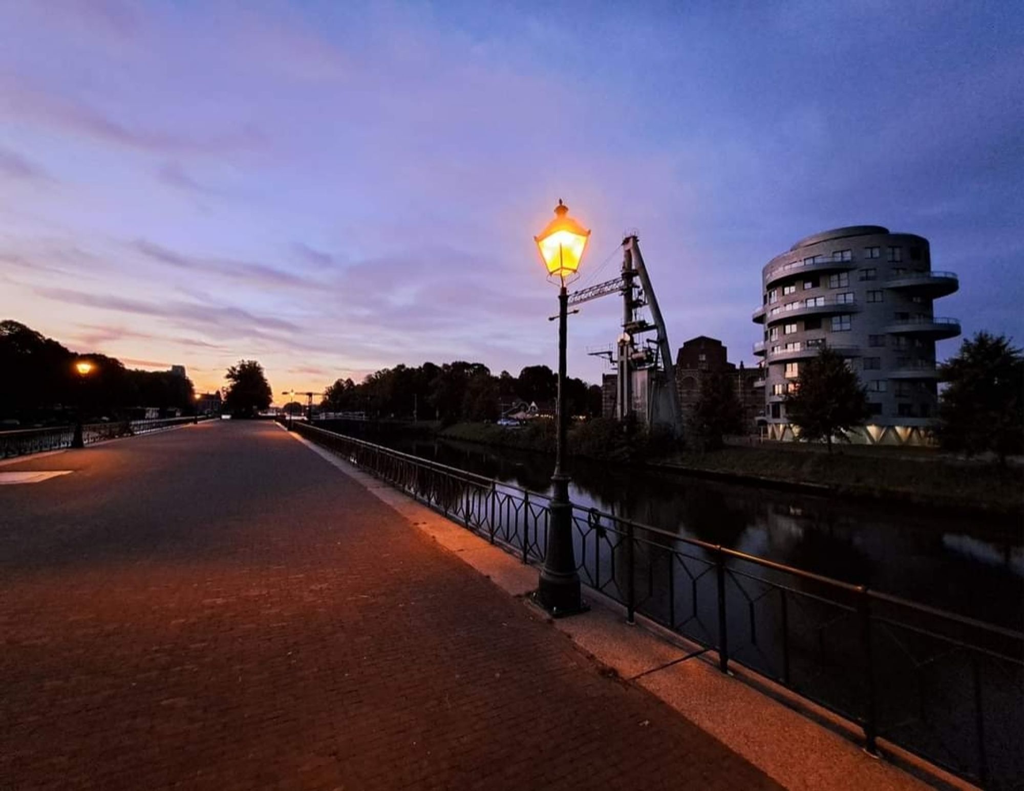 Sluis, straatlantaarn met geel licht tegen paarse lucht met vage wolkjes. Zondagochtend vroeg. Foto door Andre Russcher.