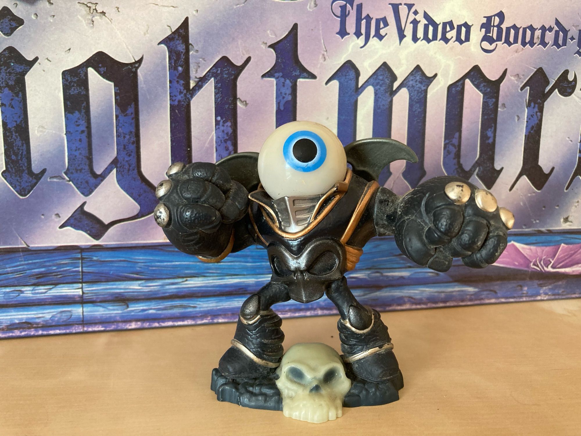 Small figurine with a blue eyeball for a head within a bulky black skull themed suit of armor.