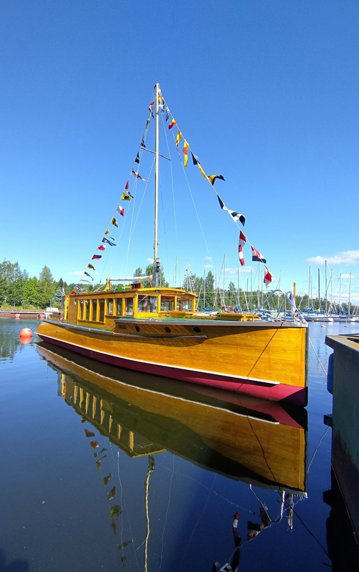 Wooden day cruiser boat in full regalia, shining golden hull against deep blue water