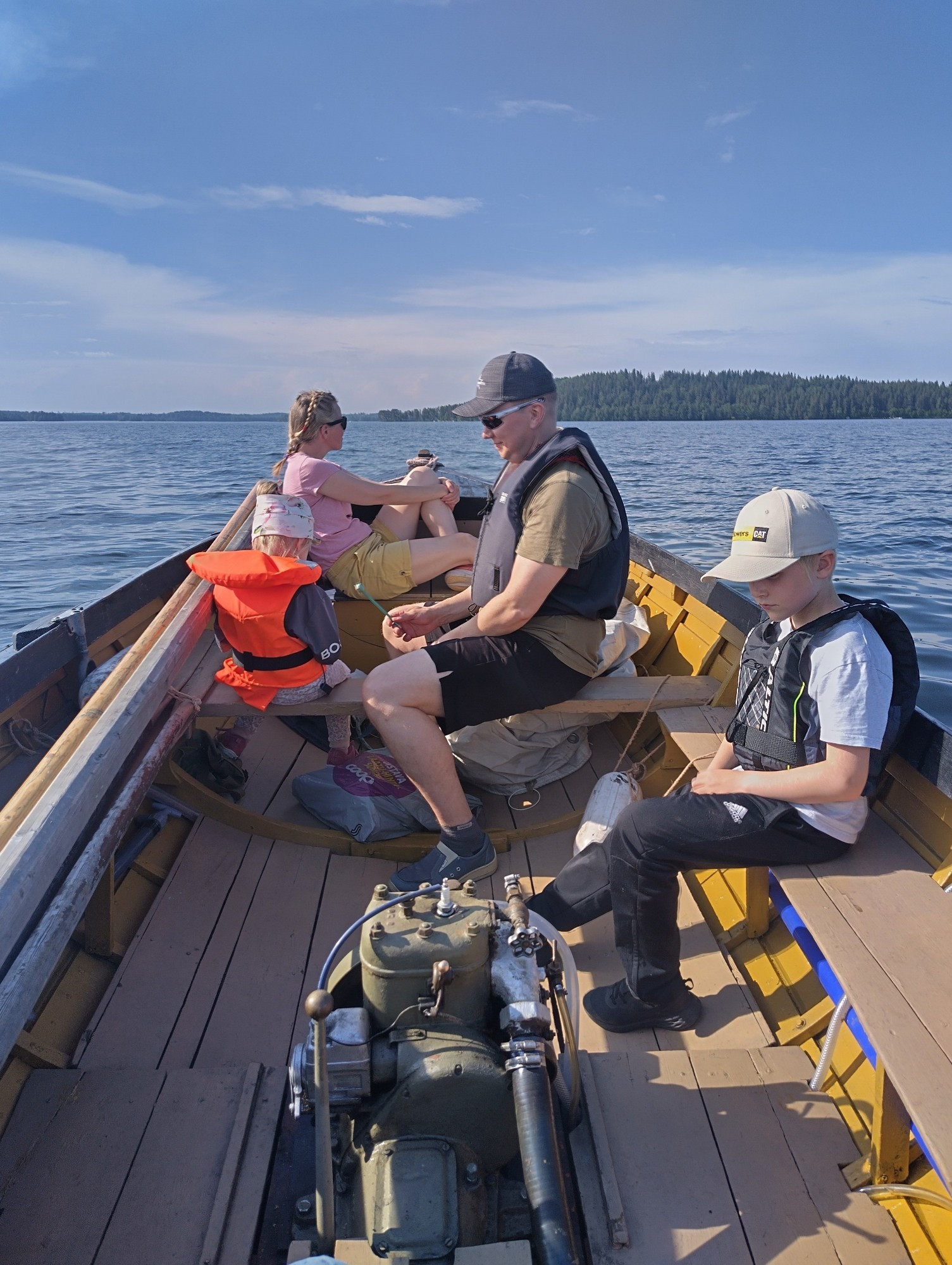 2 kids and 2 adults in an old wooden boat on a lake