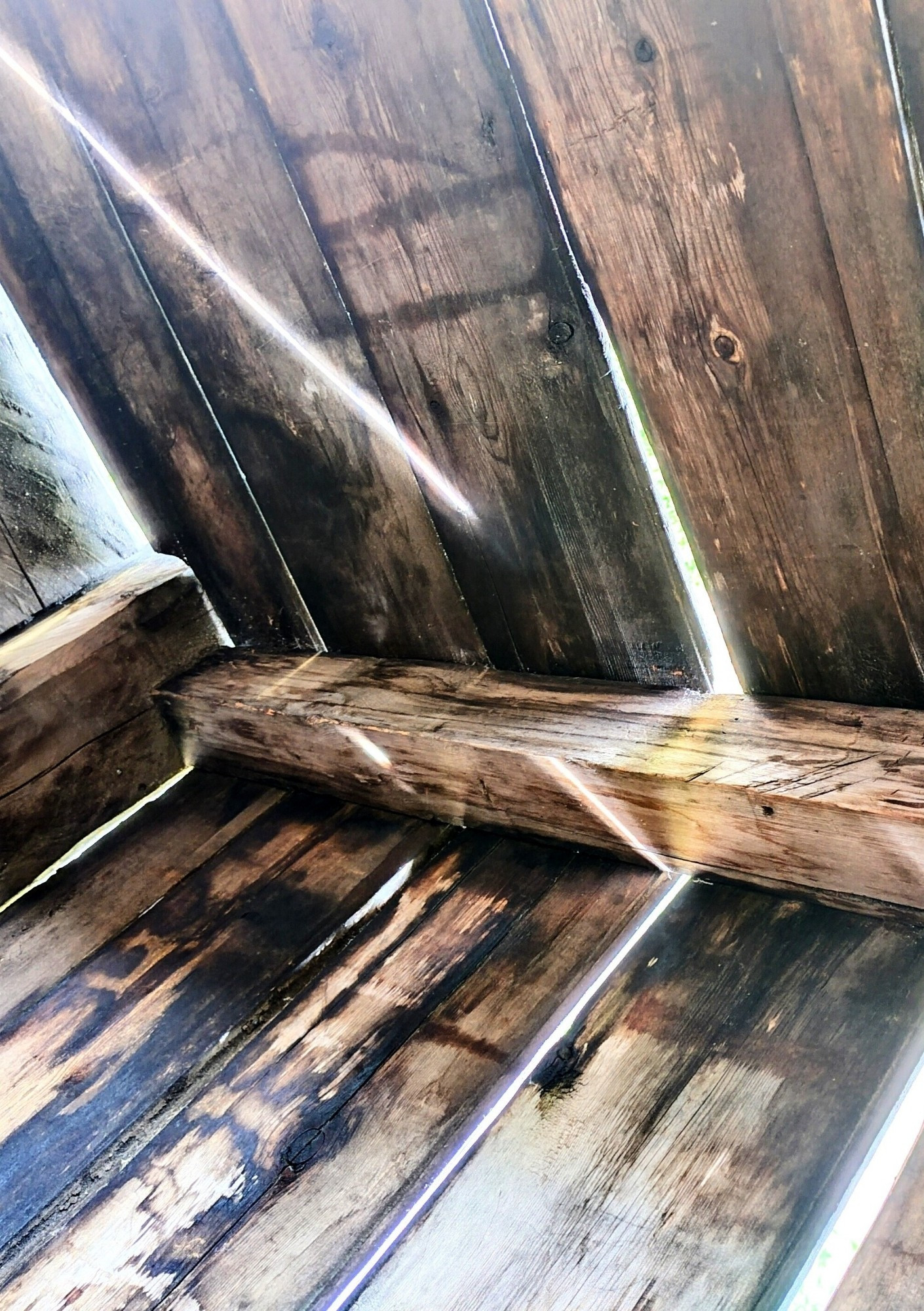 Close up of a corner inside a Lappish hut, sunshine bursting in from seams between wooden planks