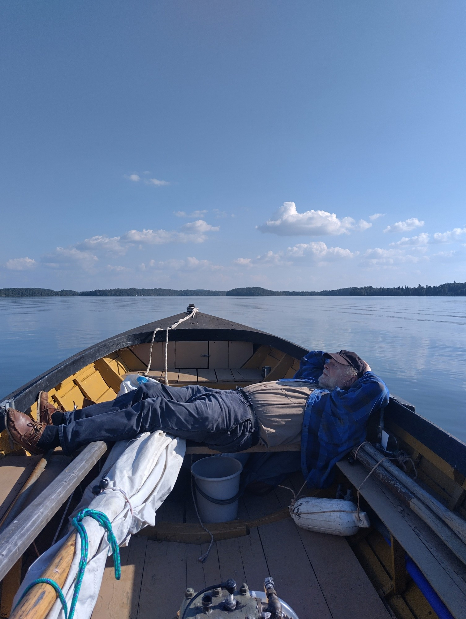 A man sleeping in a wooden boat in the middle of a lake