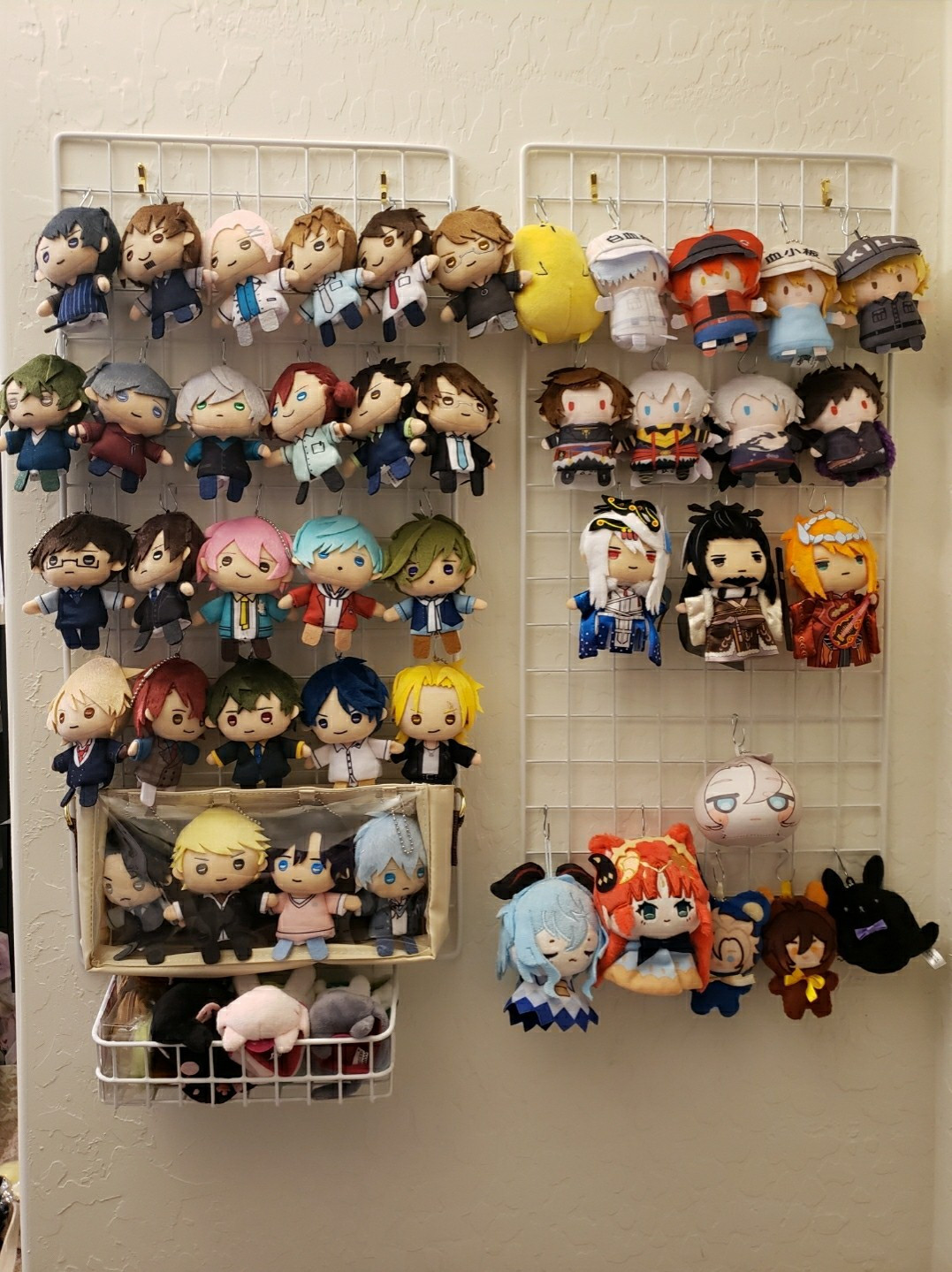 Wall with 2 vertically oriented grids, the left holding Puppella Finger Puppets from Stand My Heroes and the right holding mixed series of Cells at Work, Granblue Fantasy, Thunderbolt Fantasy, and Genshin Impact fan dolls.