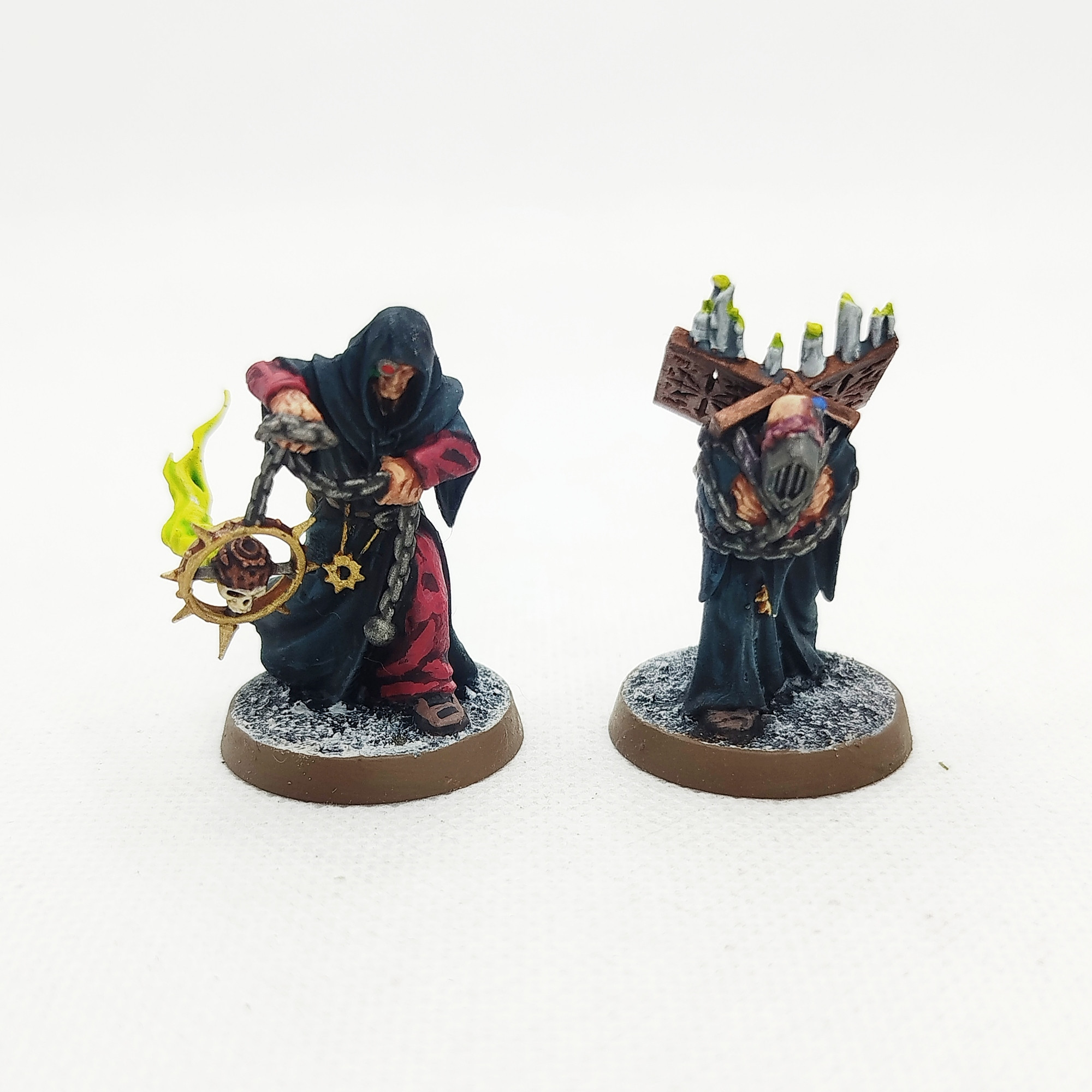 Foto de las miniaturas de los Discípulos Oscuros que acompañan al Apóstol Oscuro sobre un fondo blanco.

El discípulo oscuro de la izquierda va cubierto por una túnica negra con capucha de la que asoman ropajes rojos. Tiene un ojo biónico y porta un incesario empotrado sobre una calavera y rodeado por una estrella del caos del cual emanan llamas de color verde.

El otro discípulo lleva las mismas túnicas excepto porque no lleva capucha. Su cabeza ha sido totalmente mutilada de forma que donde debería estar su cara solo hay un altavoz. El resto de su cabeza está llena de cables. Su cuerpo y brazos están encadenados a un pequeño altar con velas que porta en su espalda para que el apóstol pueda apoyar su libro impío, lo cual lo deja con una pose encorvada.