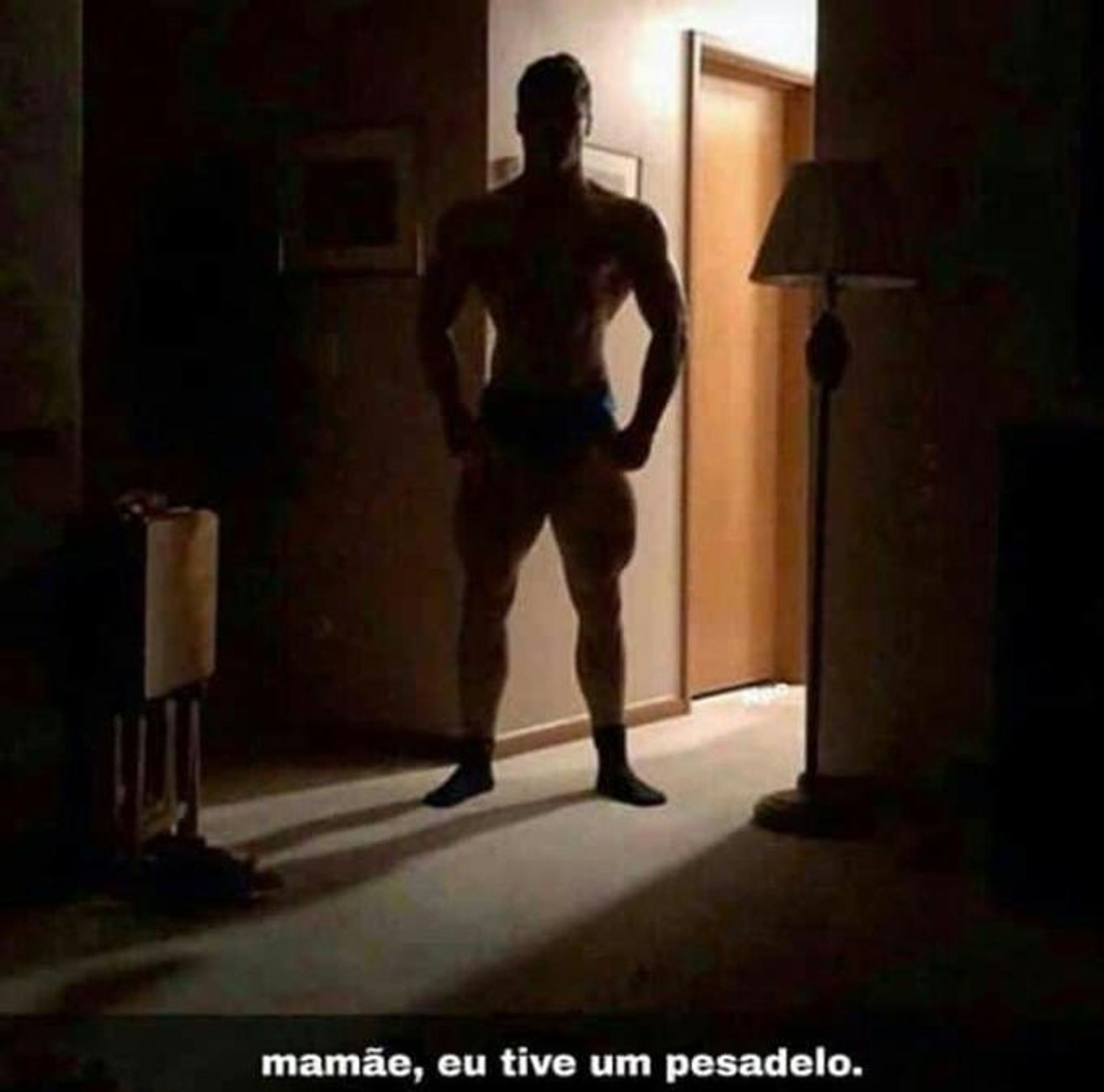 Imagem de meme mostrando um homem extremamente musculoso, parado em pé entre o corredor e o quarto de uma casa na penumbra, com a legenda "mamãe, eu tive um pesadelo".