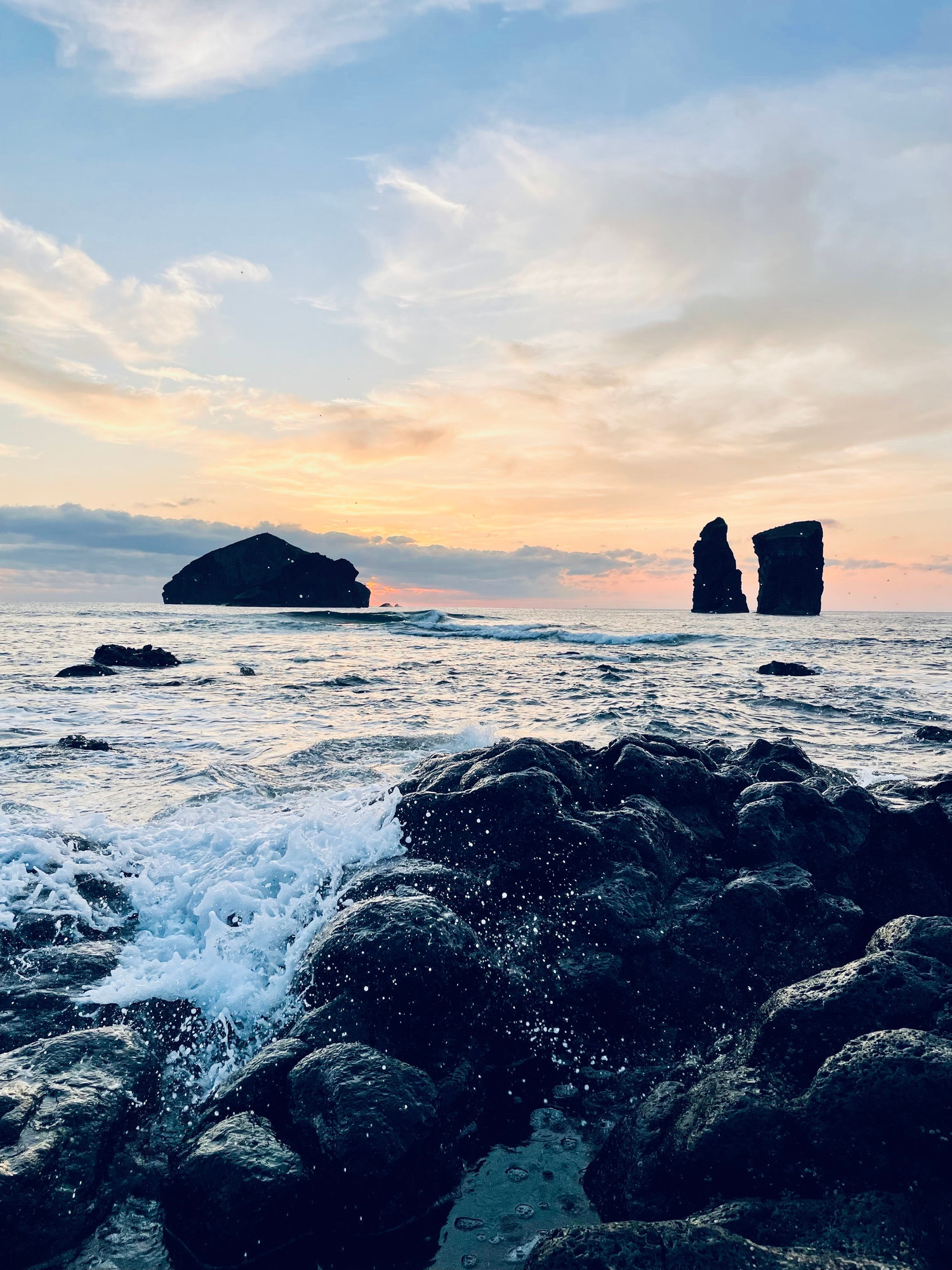 A shot of three rocks off the coast at sunset. 