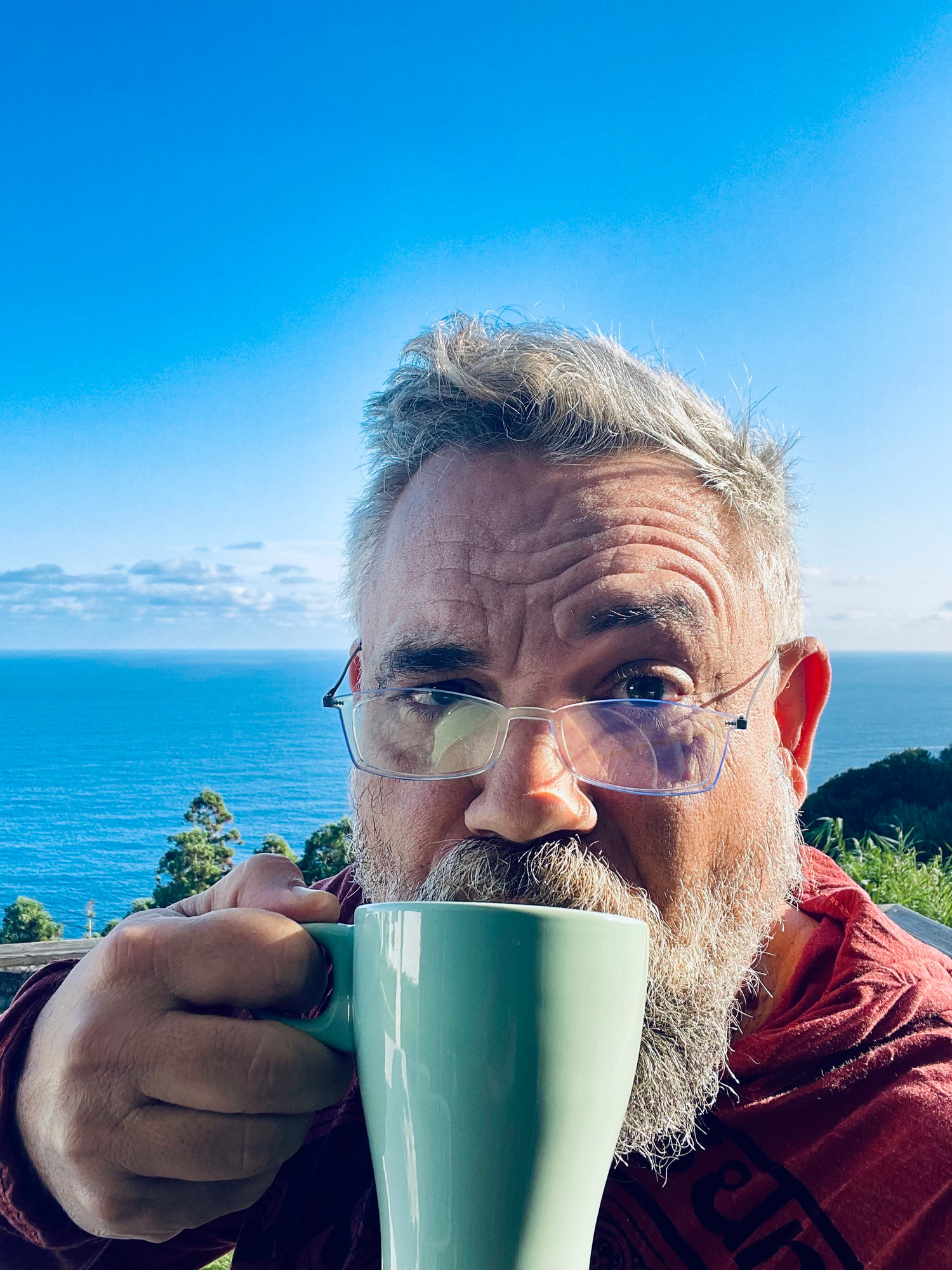 Me, w/ coffee. Ocean and volcanic rock outcrop in the background. 