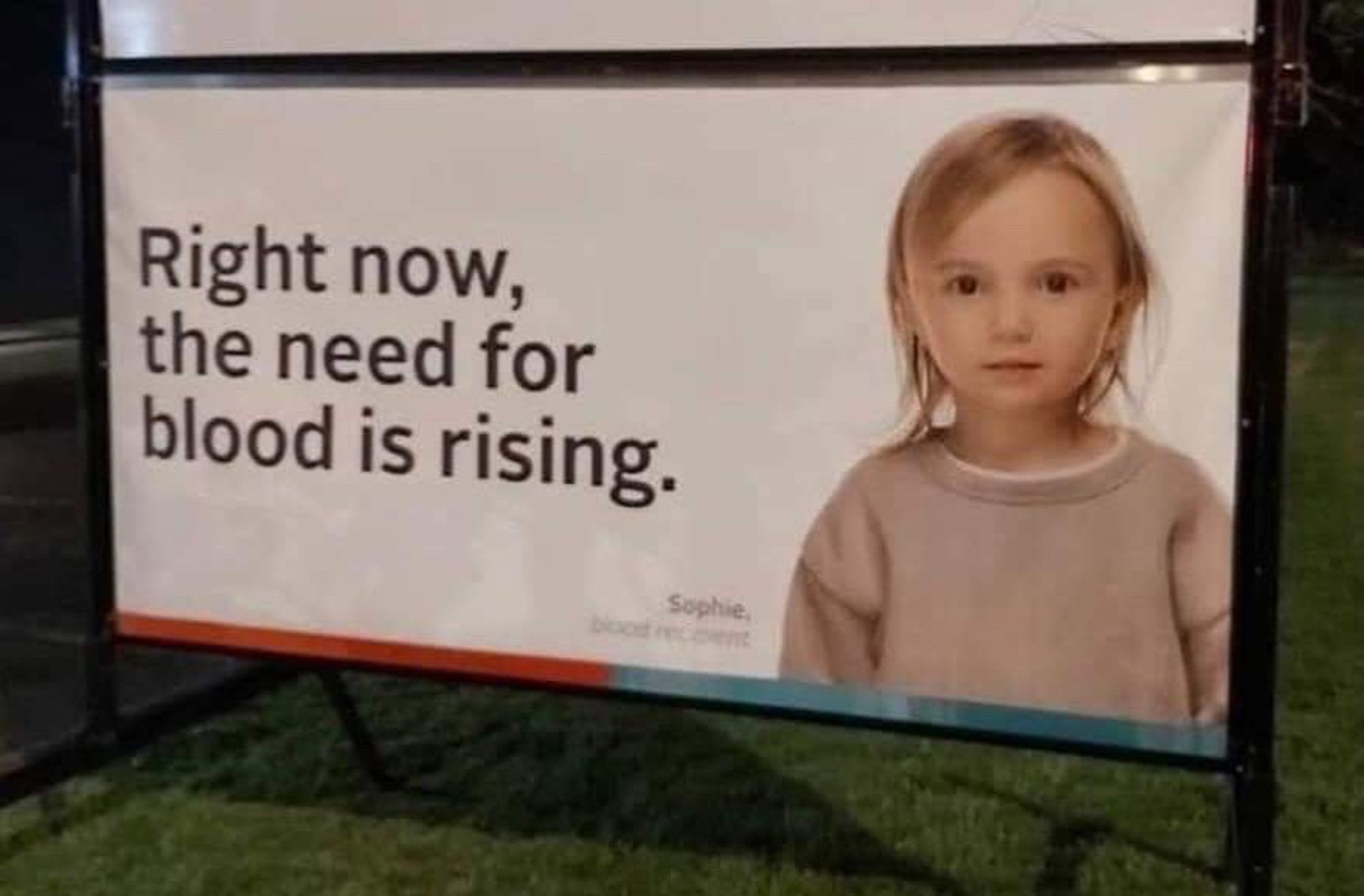 a billboard & creepy child named Sophie stares out at you. the caption reads "Right now,the need for blood is rising"😳