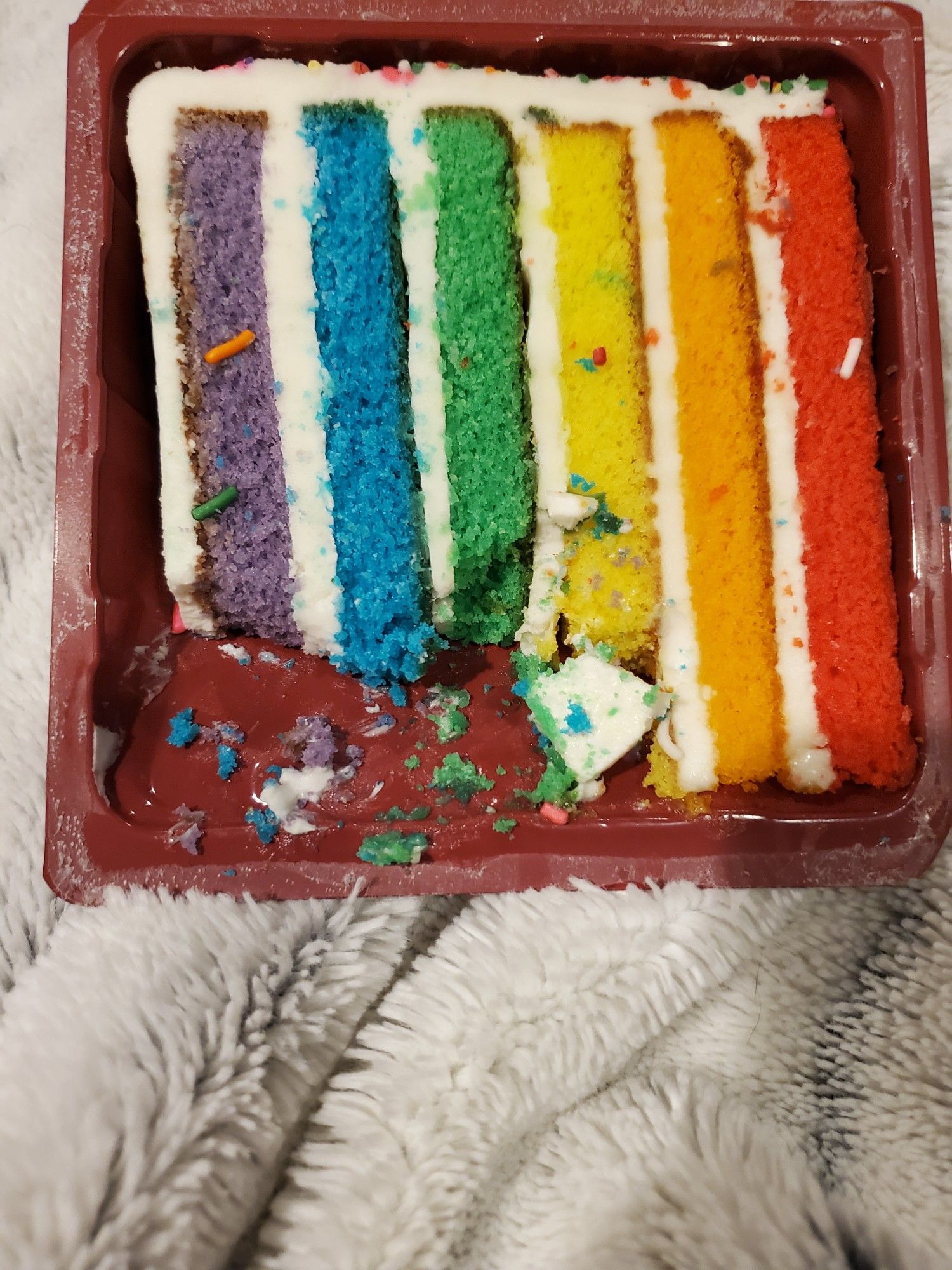 A beautiful rainbow layer cake...with a few bites taken out of blue, green and purple layers