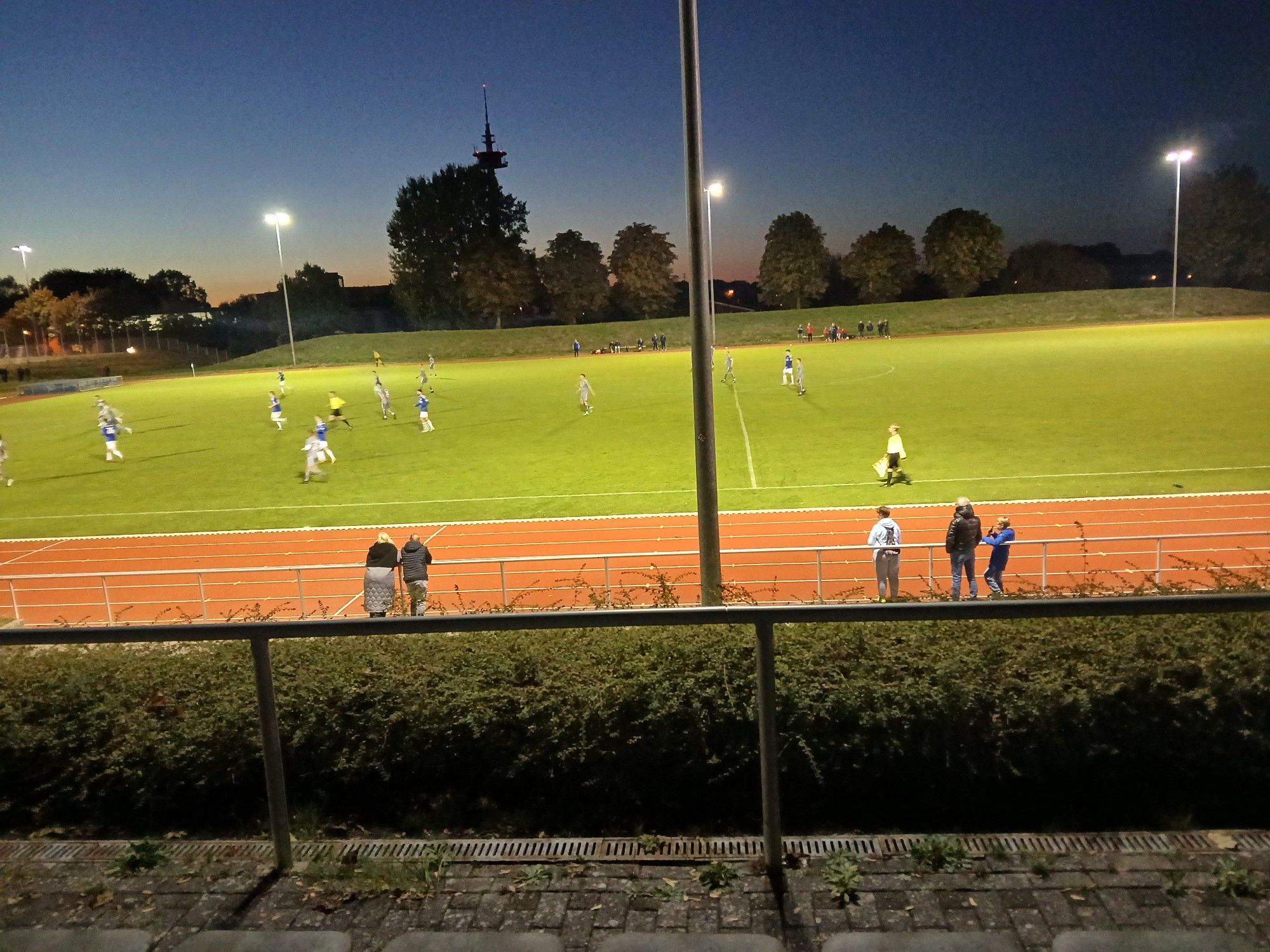 Rasenplatz im Stadion Rensefelder Weg mit eingeschaltetem Flutlicht.