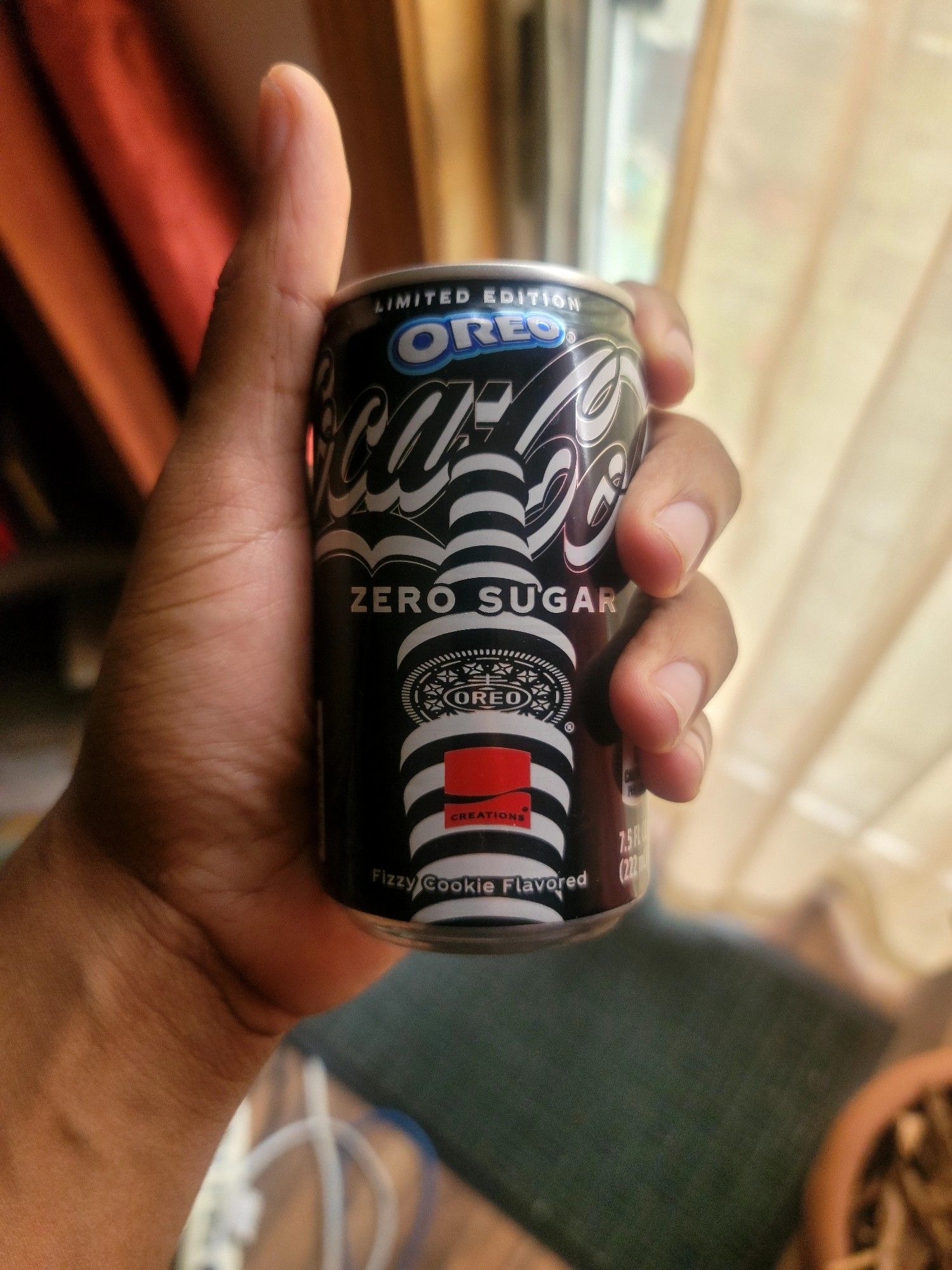 Me holding a can of oreo coke, it has a a somewhat hypnotic looking black and white cylindrical pattern design that's kinda cool, broken up with a red square.