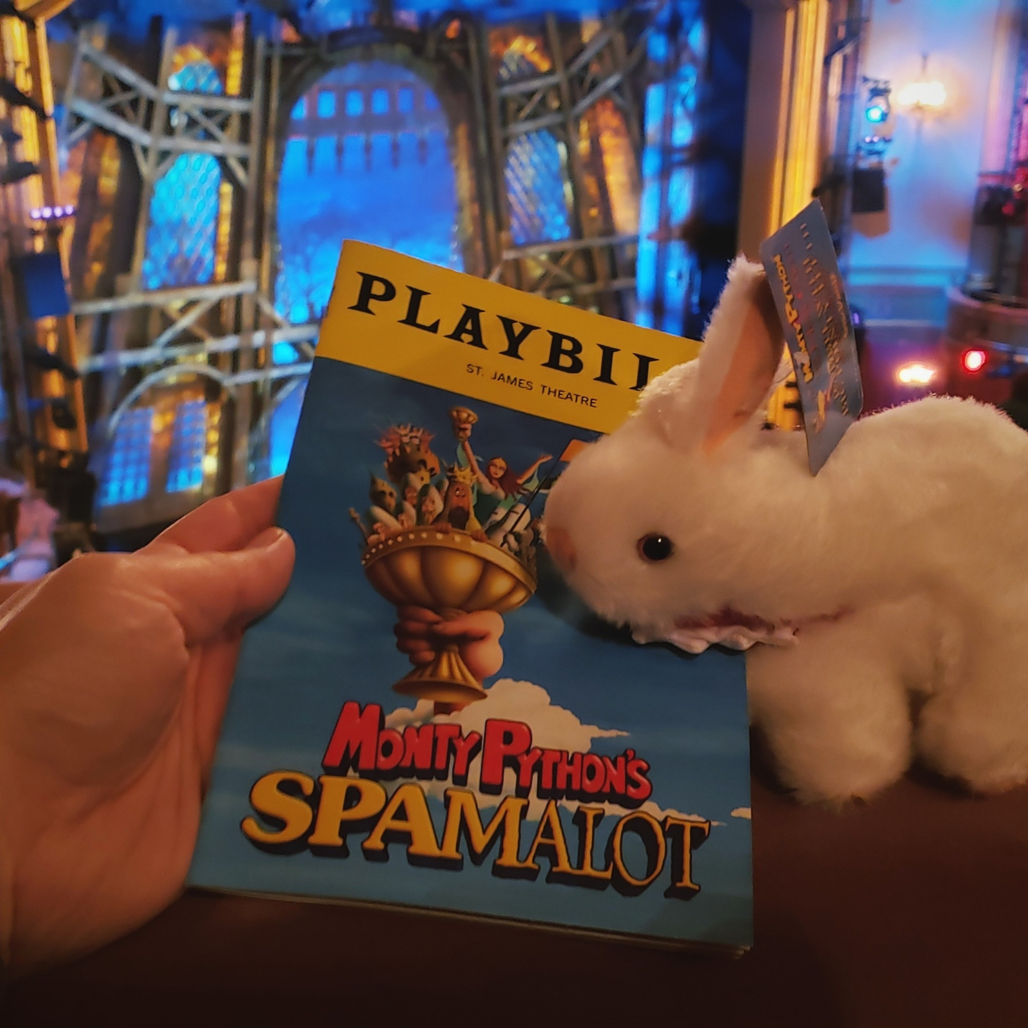 Playbill for Monty Python's Spamalot being bitten by a stuffed killer rabbit.