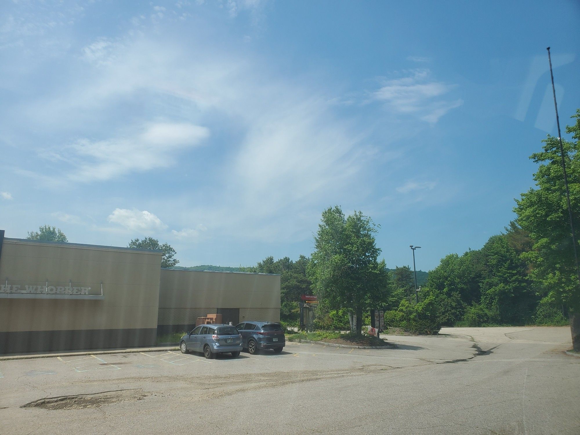 Old run-down Burger King with a couple of cars and a huge pot-hole.