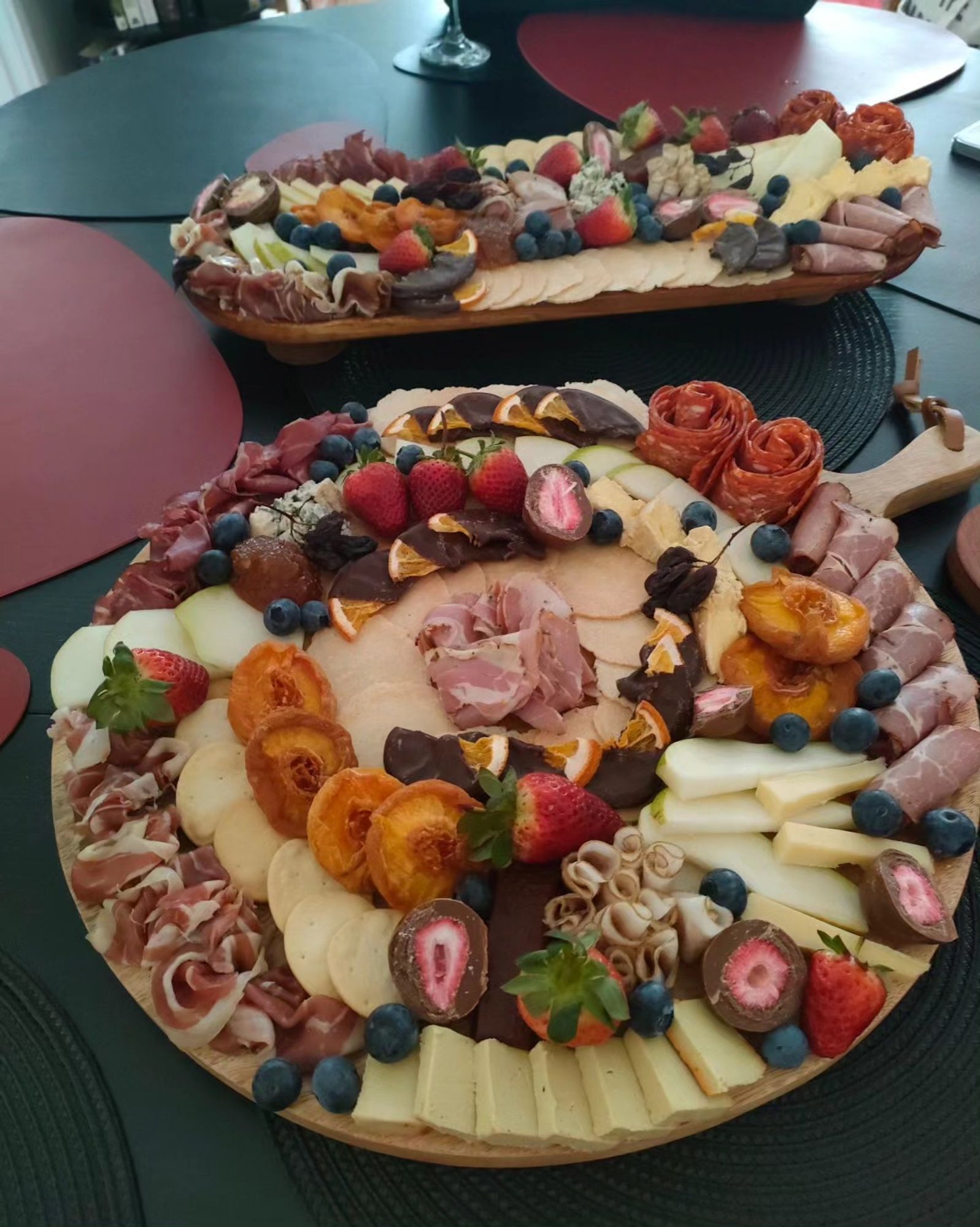 An extremely artistic cheeseboard, featuring multiple different kinds of cheese, charcuterie and fruit