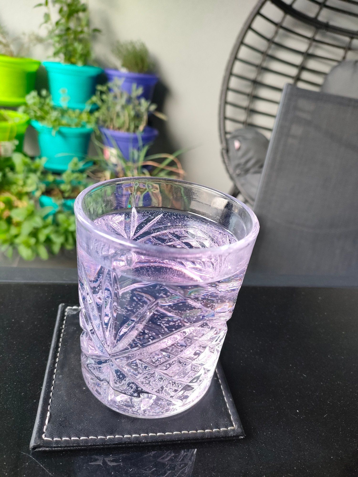 A delicate lavender gin and tonic in front of a balcony herb garden