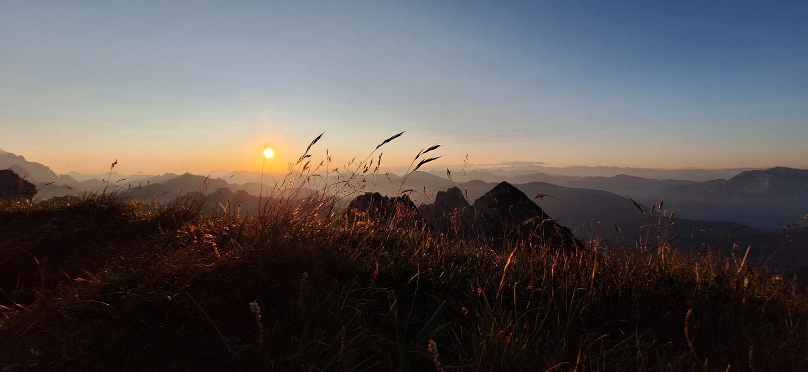 Avondzon in Slovenië. Wuivende hakmen, zon zakt achter de bergen