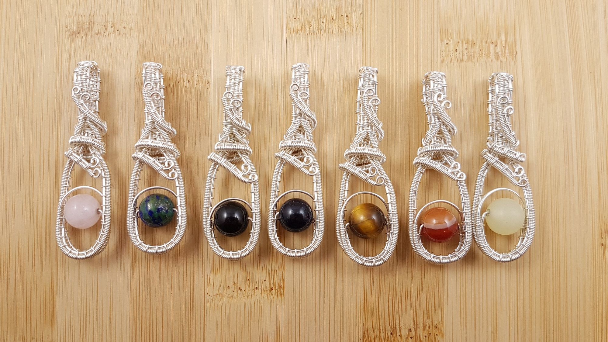 Row of coloured bead and silver wire fidget pendants.