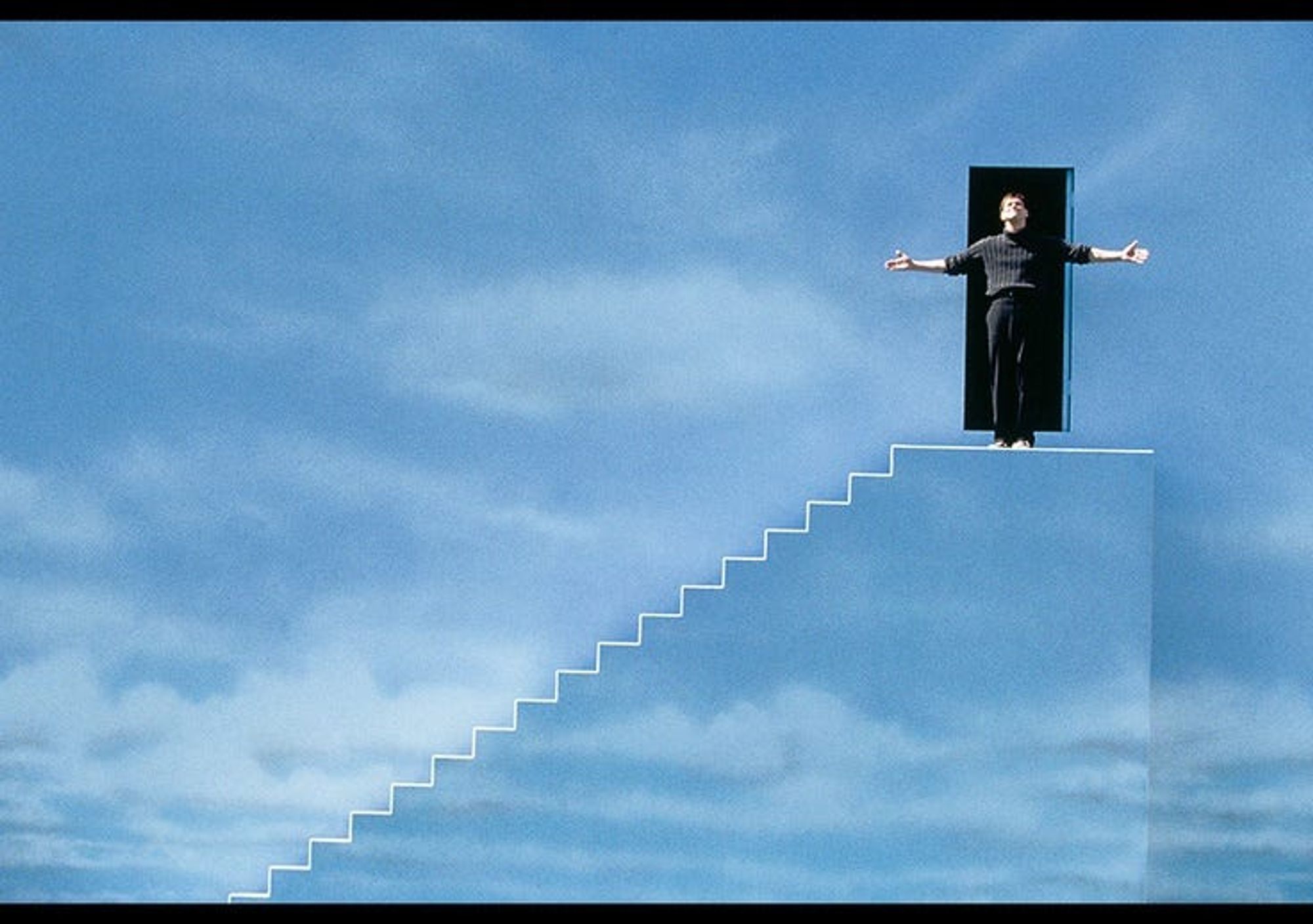 the ending scene of the truman show, where (spoiler alert) he stands in front of the door at the edge of the show's universe, arms outstretched. the wall, and the staircase that goes up it, is painted as if it were a cloudy blue sky