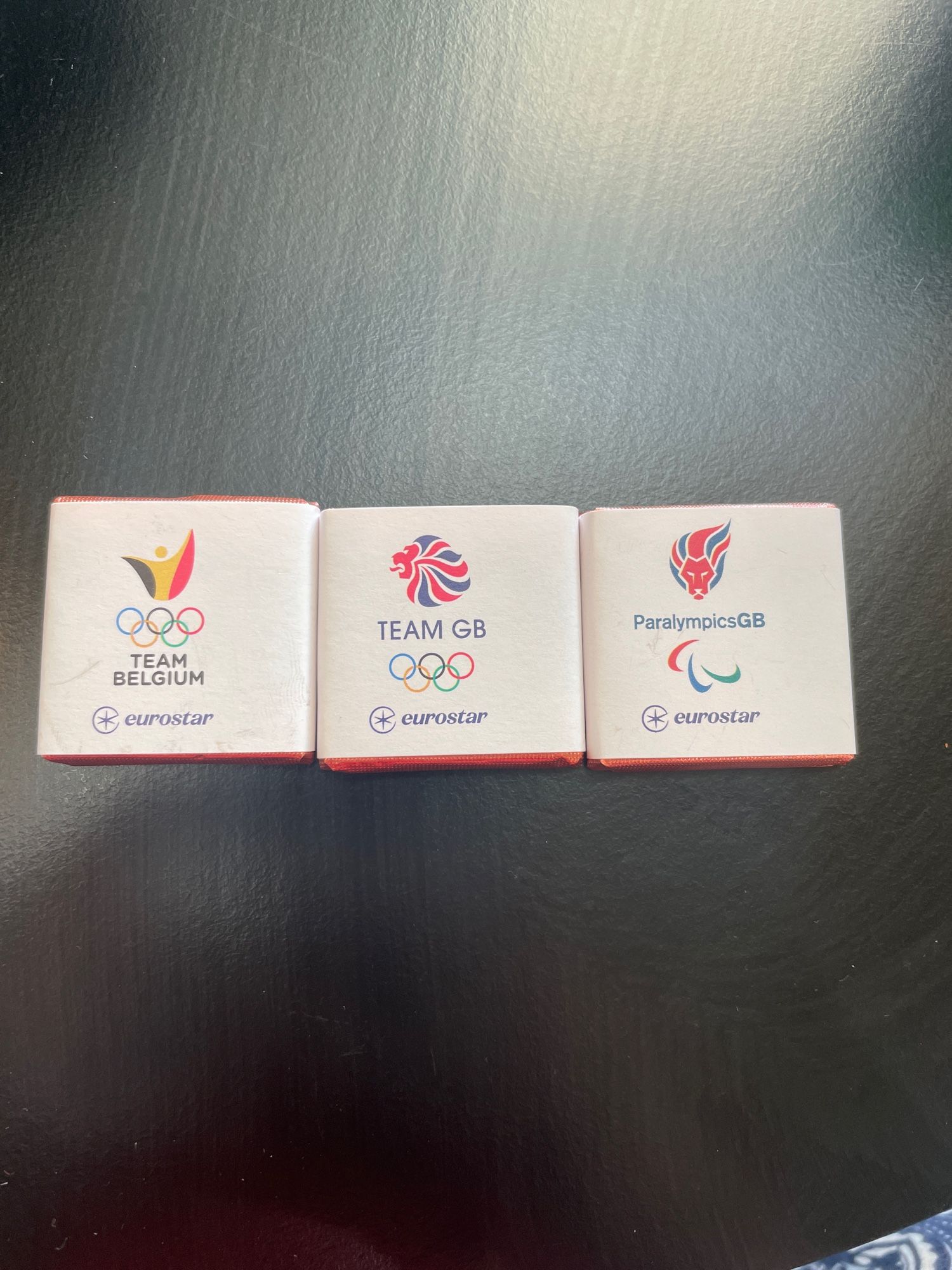 Three small wrapped squares of chocolate with olympic branding, one is team Belgium, one team GB and one paralympics GB