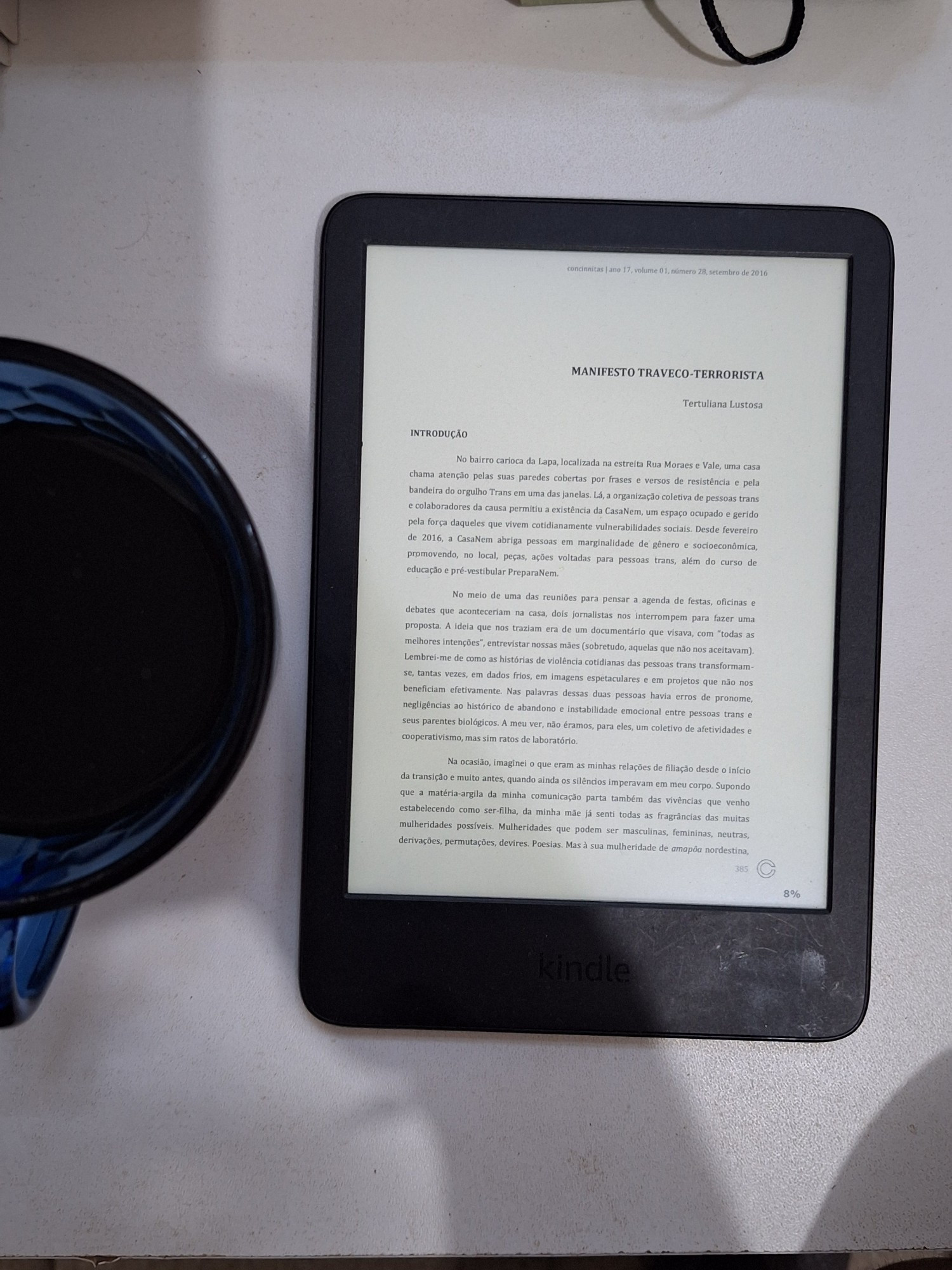 Kindle sobre a mesa ligado ao lado de uma xícara de café