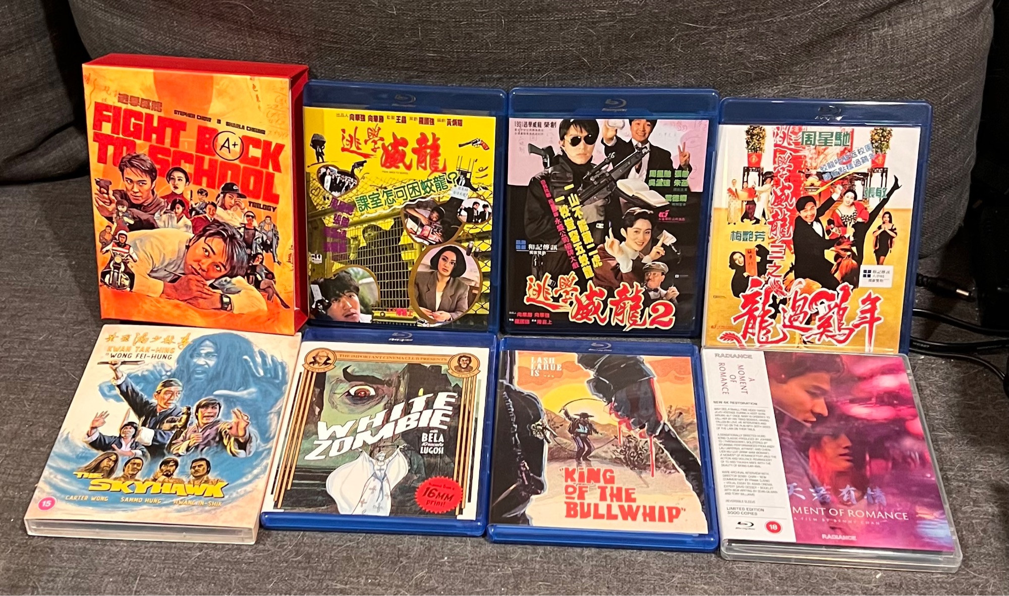 Photo of various Blu-rays laid out. 88 Films' box set of Fight Back to School 1-3, Eureka's release of Tge Skyhawk, Radiance's release of A Moment of Romance, and Gold Ninja's White Zombie and King of the Bullwhip.