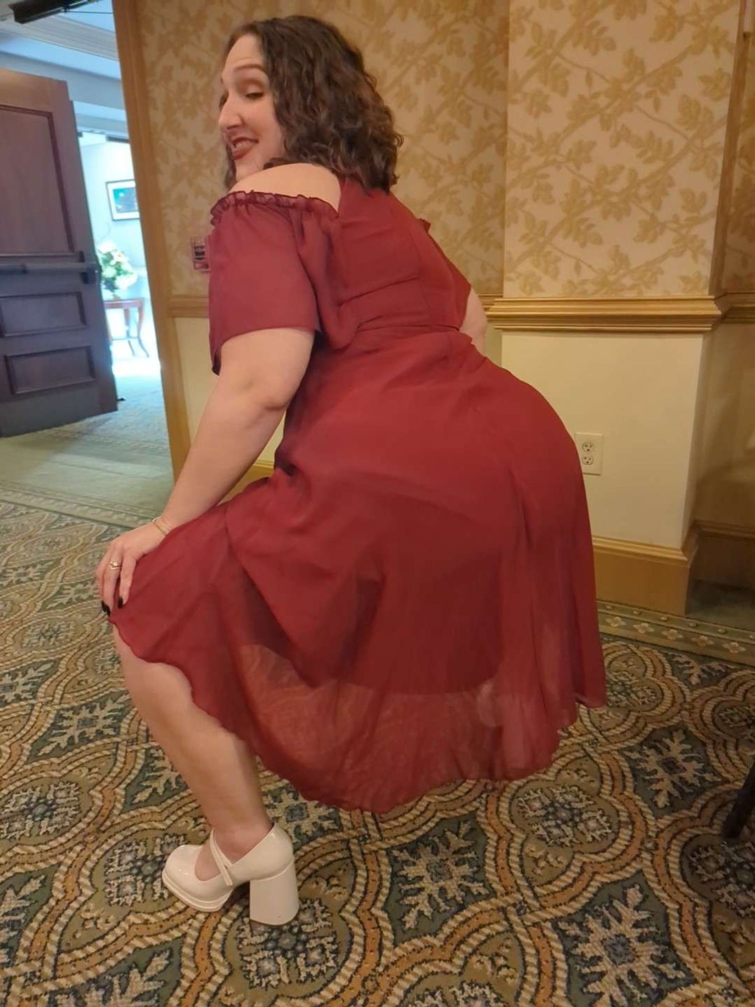 photo of myself, squatting with my butt out, dressed in a nice red dress and white chunky heels