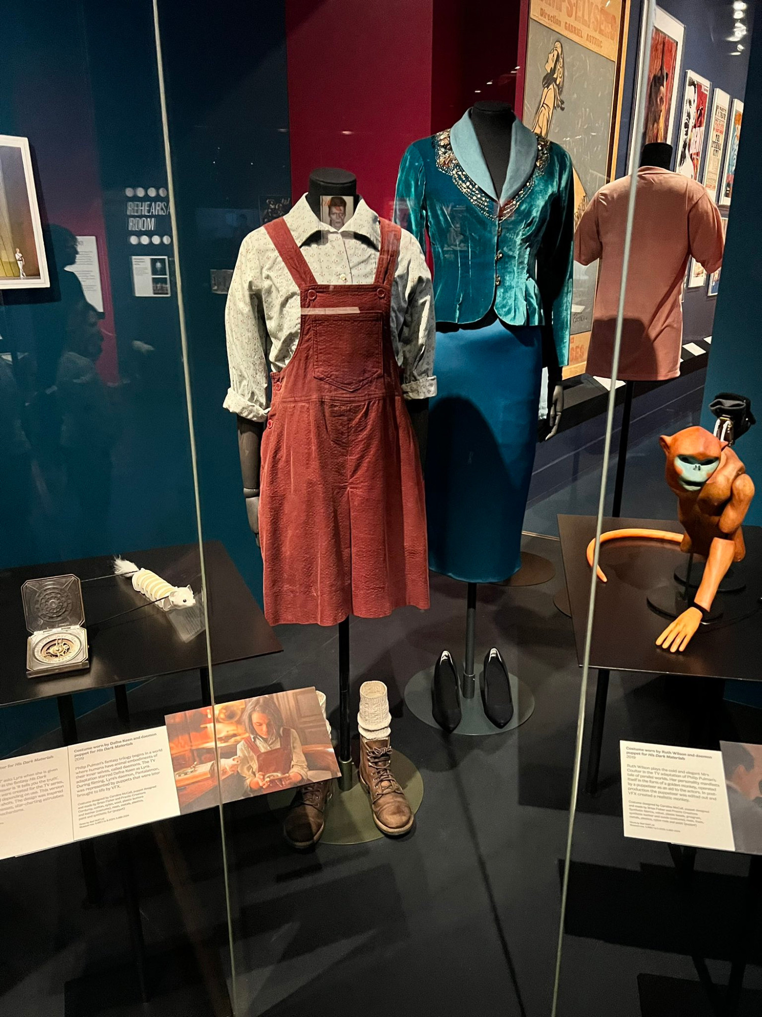 A view from a display in the Theatre & Performance Gallery at The Victoria and Albert Museum (London), featuring many items from the HIS DARK MATERIALS TV-show production, including an alethiometer, a Pan and a Golden Monkey puppets or costumes from Lyra and Mrs Coulter.