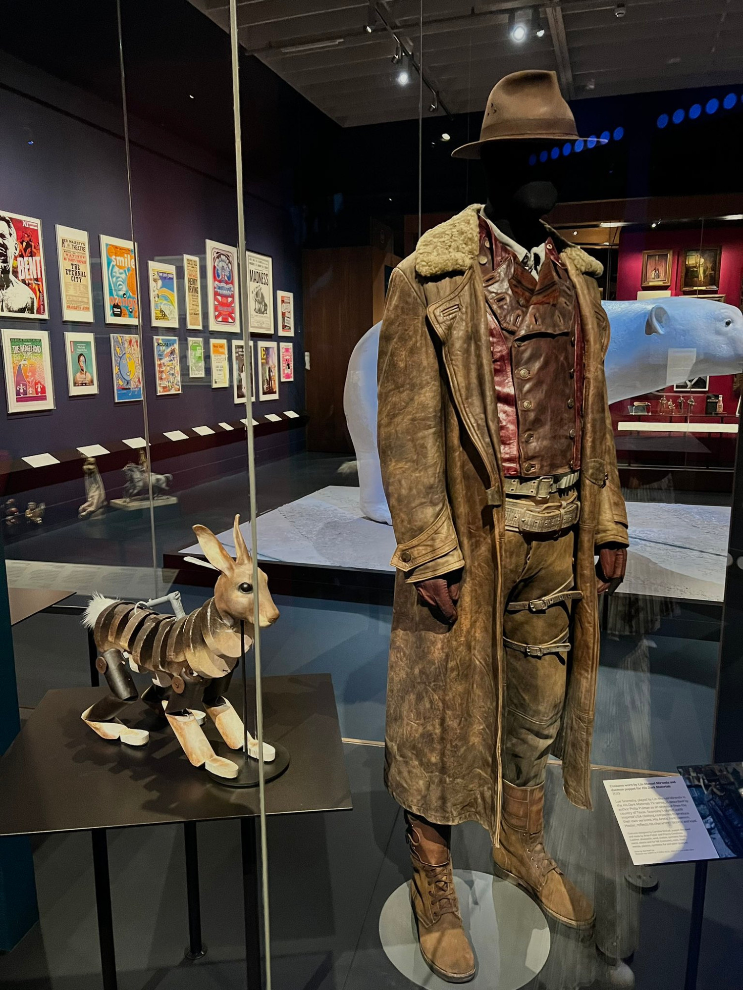 A view from a display at the Theatre & Performance Gallery at The Victoria and Albert Museum (London), featuring many items from the HIS DARK MATERIALS TV-show production, including a lovely Hester puppet and a costume from Lee Scoresby, with a Scale 1 Iorek mock-up in the background.