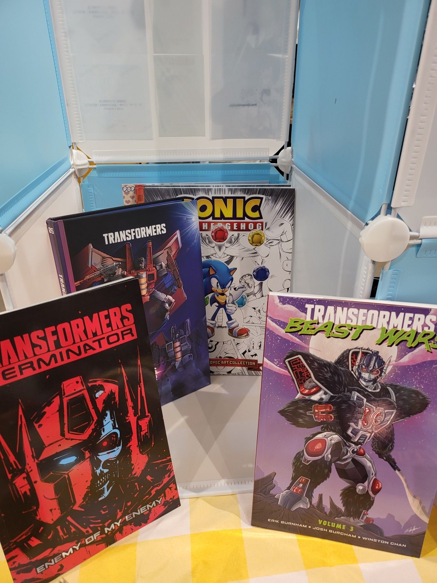 A selection of books including the Sonic IDW Art Collection, Beast Wars Vol 3, Transformers vs. The Terminator, and TF: Horrors Near and Far featuring my Wreckers series.