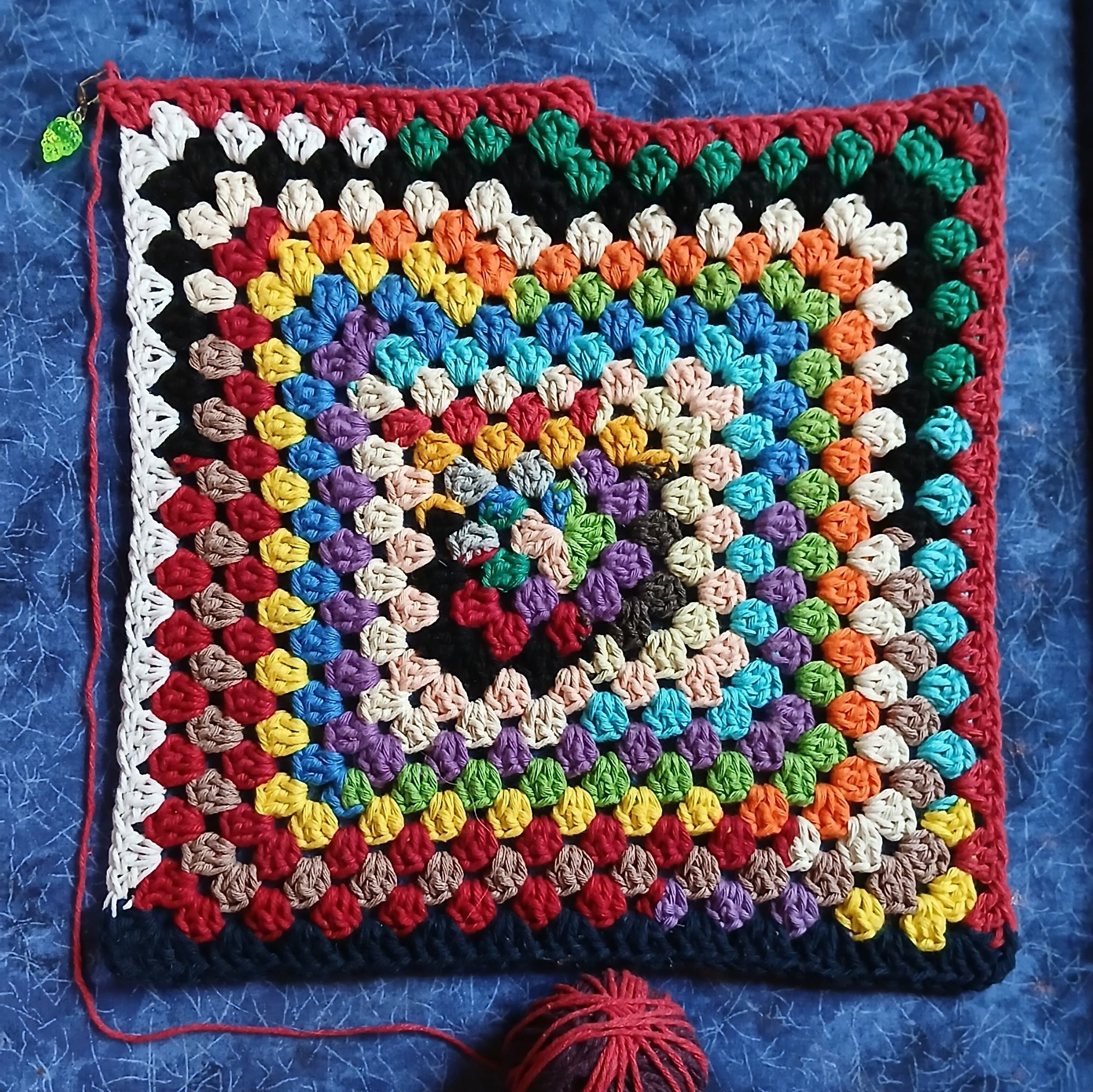 A large crocheted granny square in many random colours